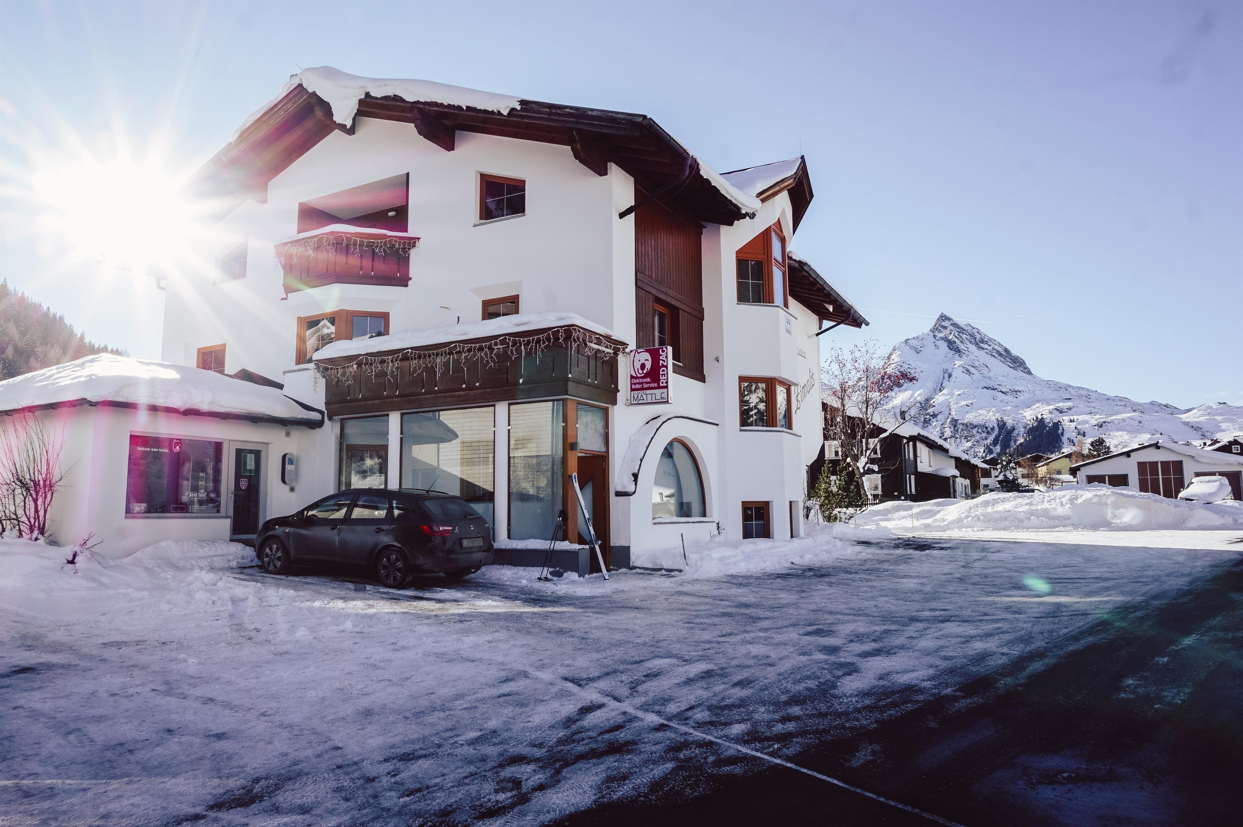 A modern building in a snowy landscape. In the background, mountains and a clear sky can be seen.