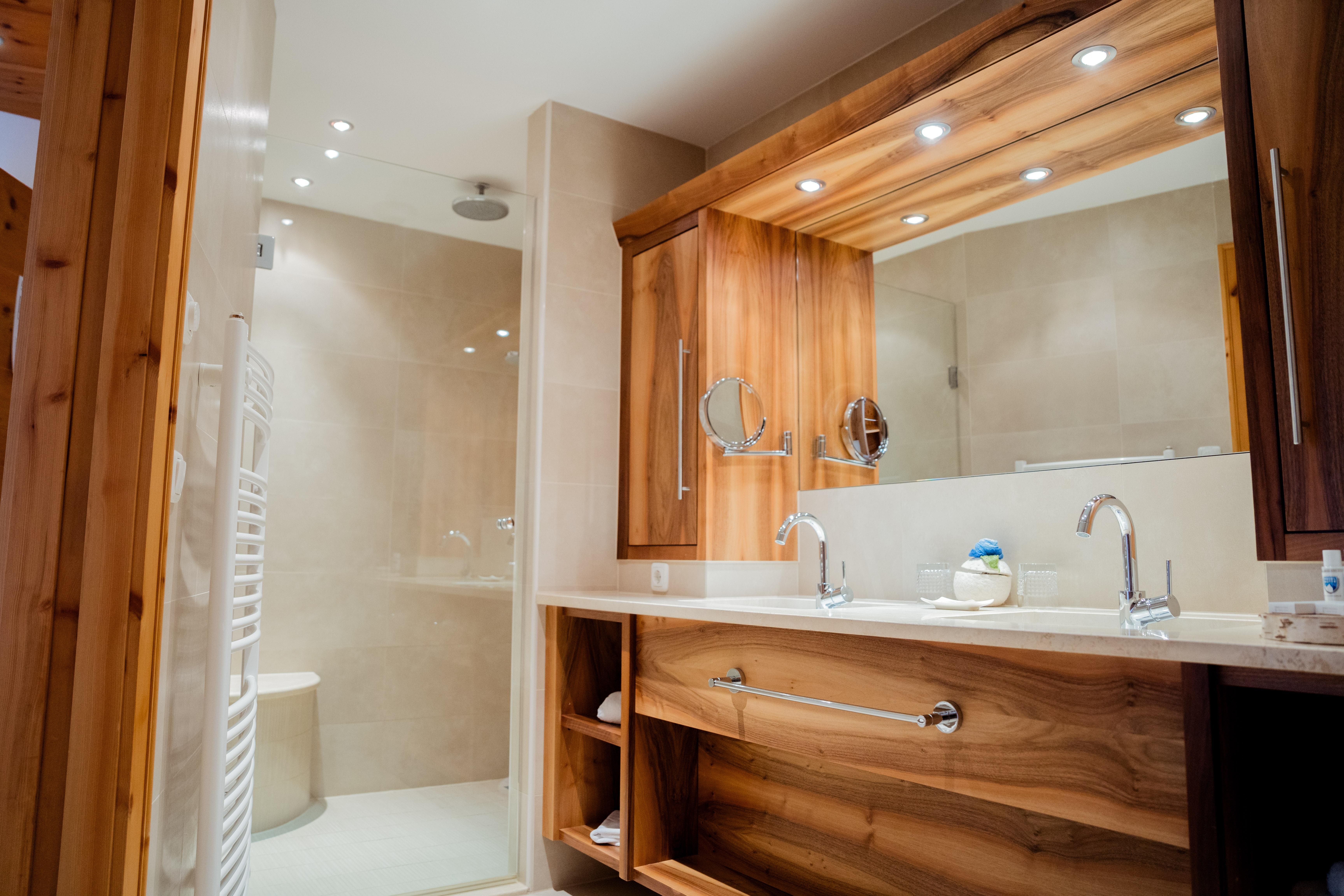 A modern bathroom with wood details and a sink. The shower cabin is clearly visible in the background.