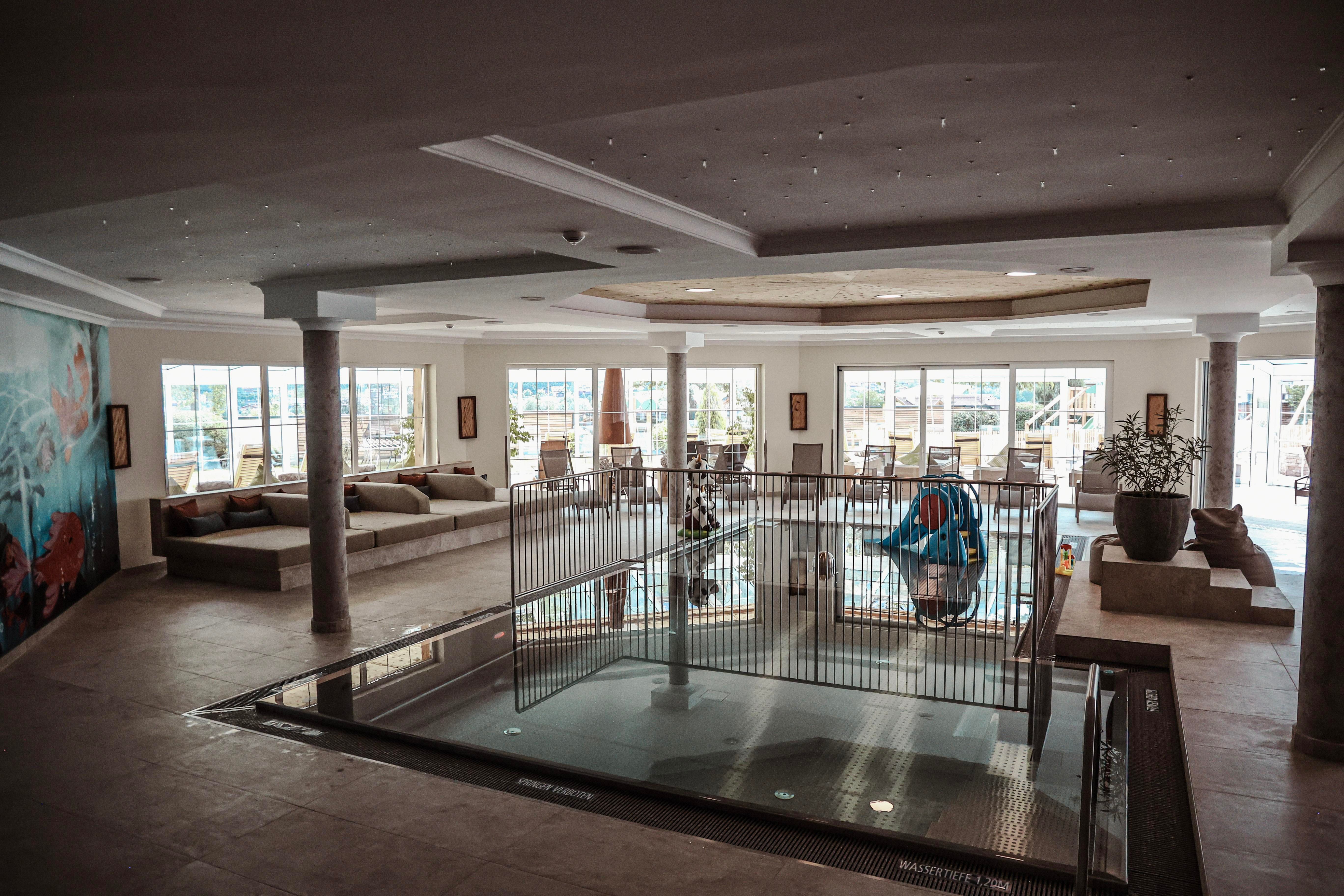 A modern wellness area with a small pool and comfortable seating. Bright windows offer a beautiful view outside.