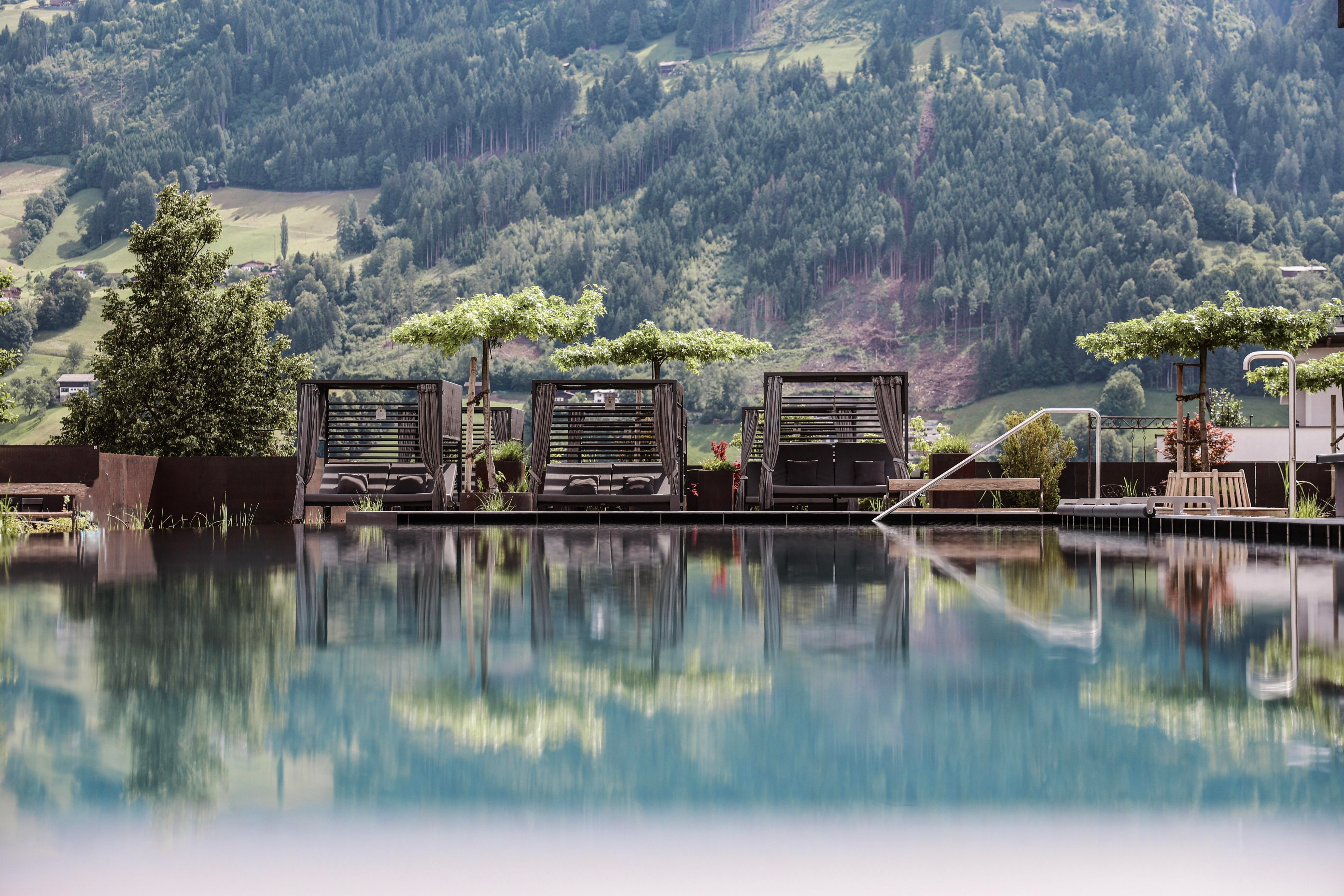 A stylish pool with views of green mountains and relaxing lounge chairs. The tranquil atmosphere invites relaxation and enjoyment.
