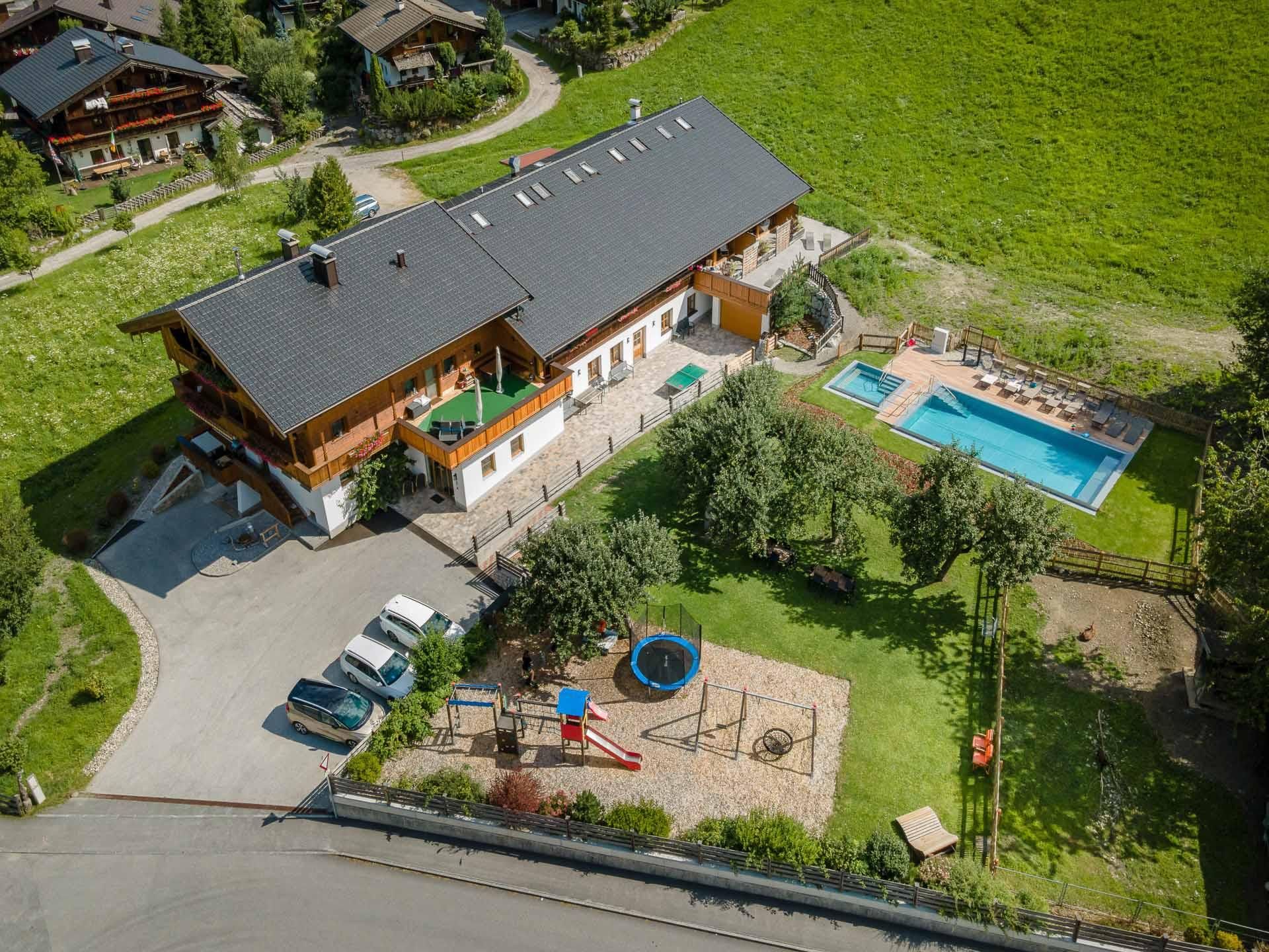 A beautiful country house with a pool and a large garden. Nearby, there are playground equipment and parking spaces.