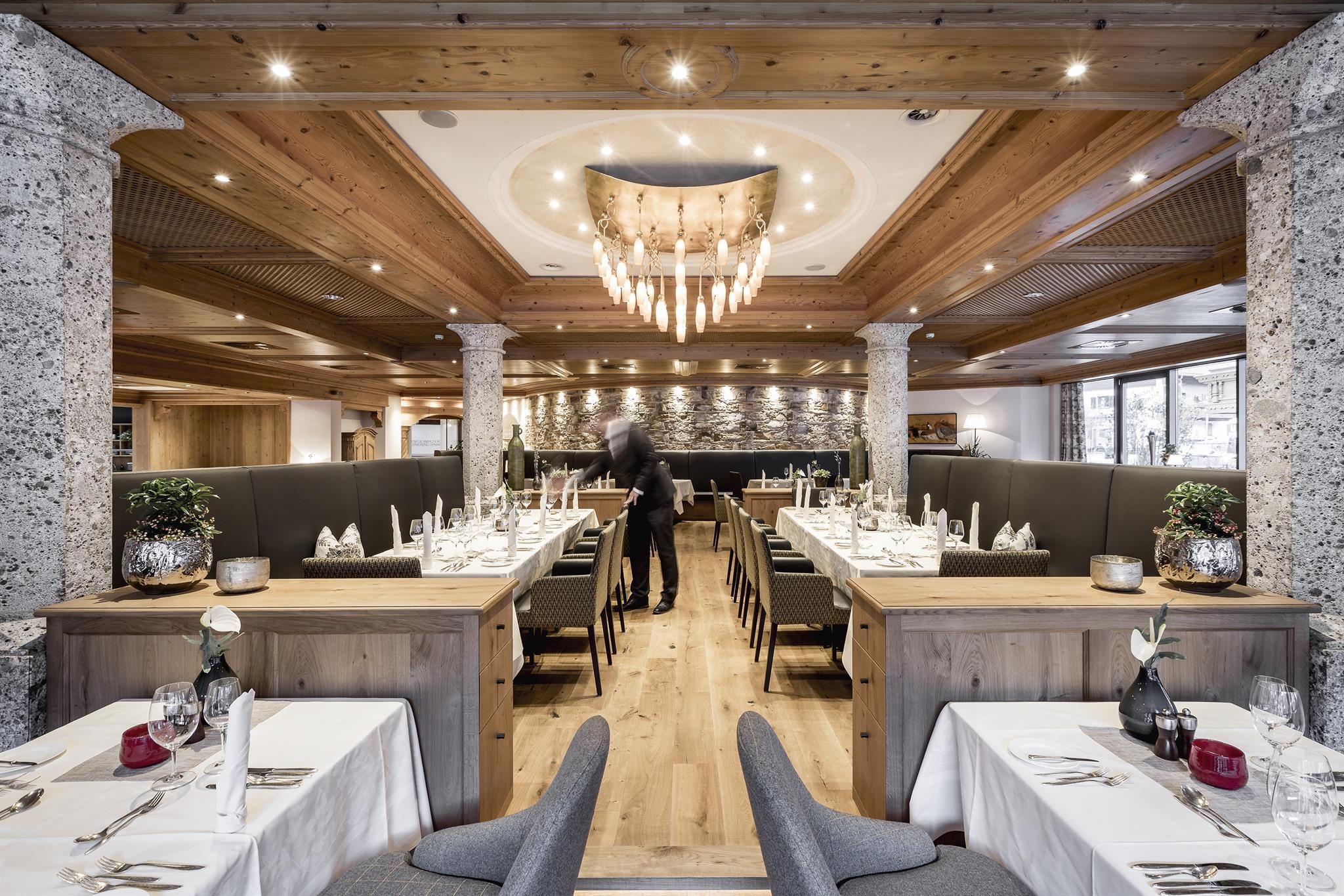 An elegant restaurant with wood decor and modern furniture. The tables are festively set, and the lighting creates a cozy atmosphere.