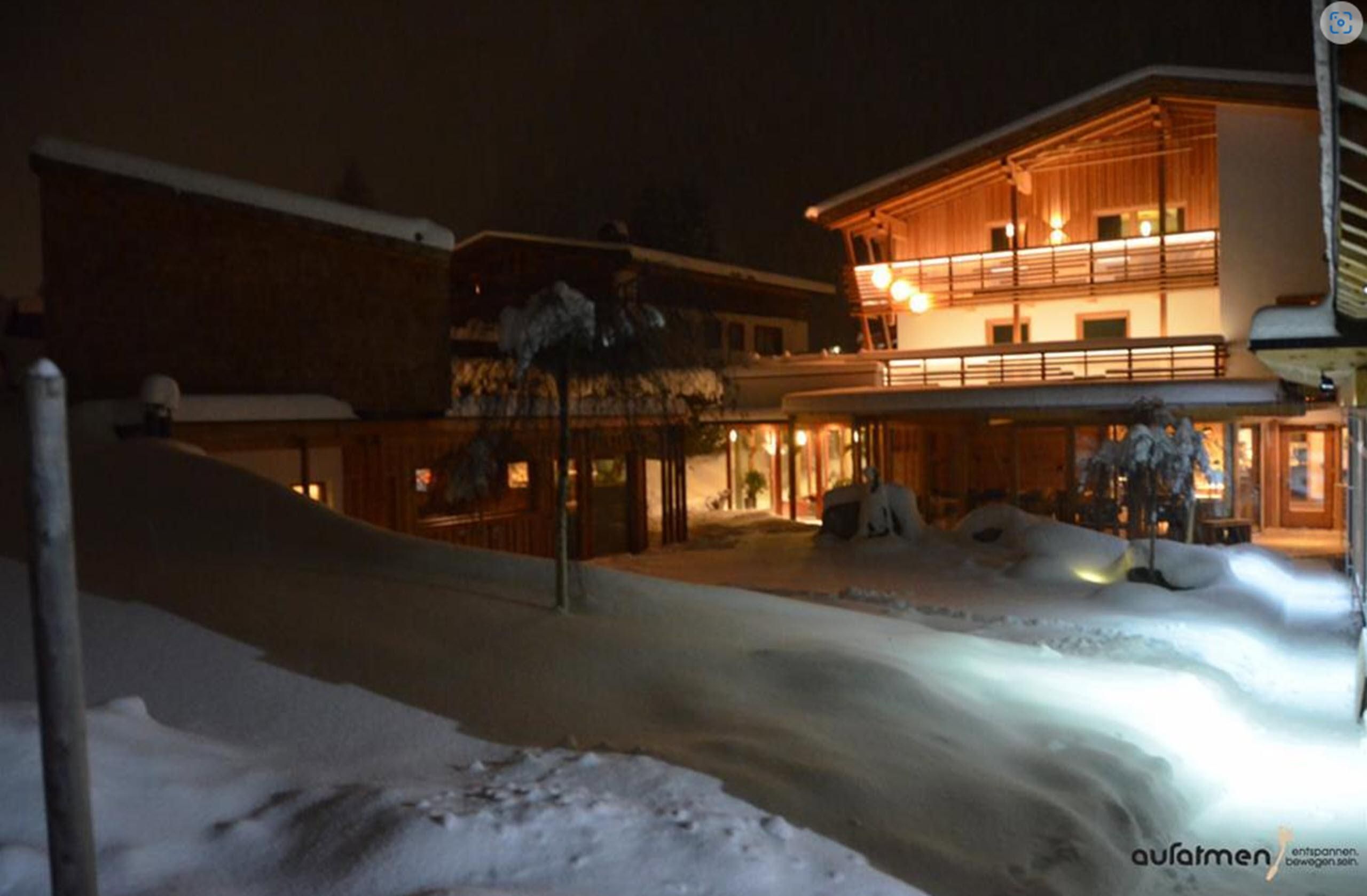 A modern building in a snowy environment at night. Soft light radiates from the windows, creating a cozy atmosphere.