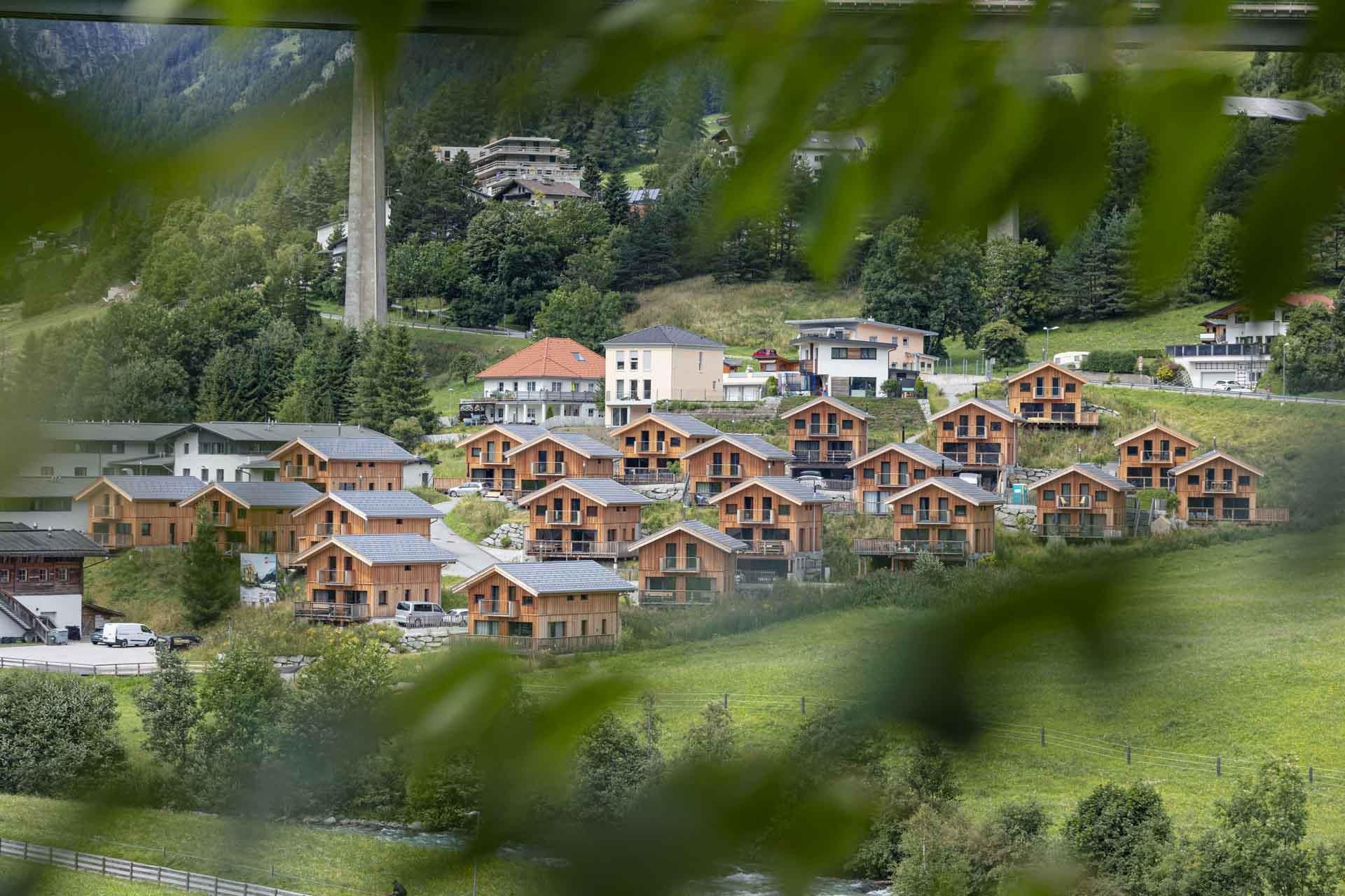A picturesque mountain landscape with several wooden chalets. Surrounded by green meadows and trees, the scene gives a cozy atmosphere.