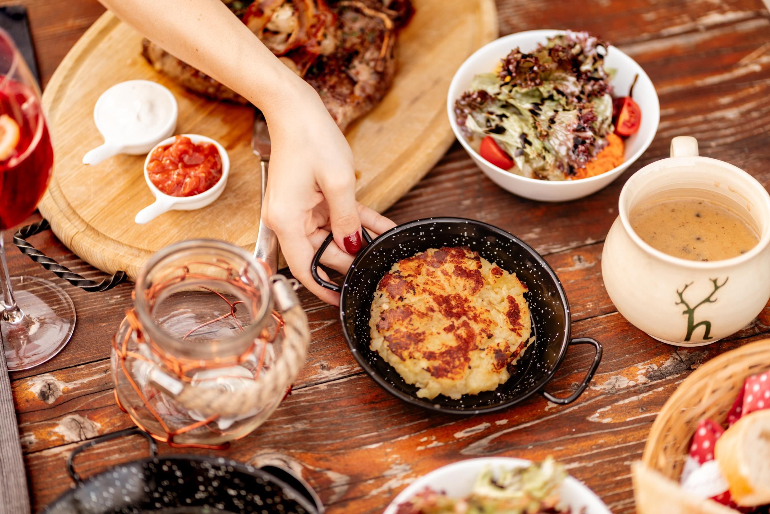 A delicious dish in a small pan, surrounded by various side dishes and drinks. The entire scene conveys an inviting atmosphere for a communal meal.