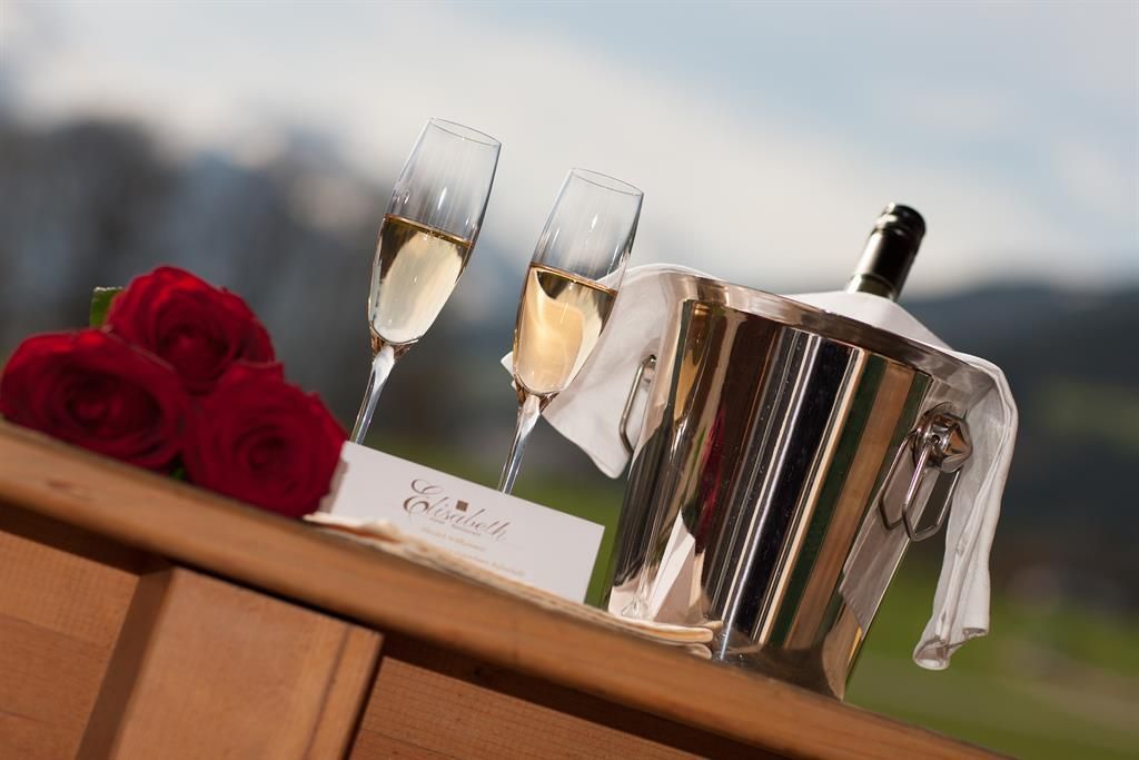 An elegant champagne set with two glasses and an ice box. Red roses give the arrangement a romantic atmosphere.