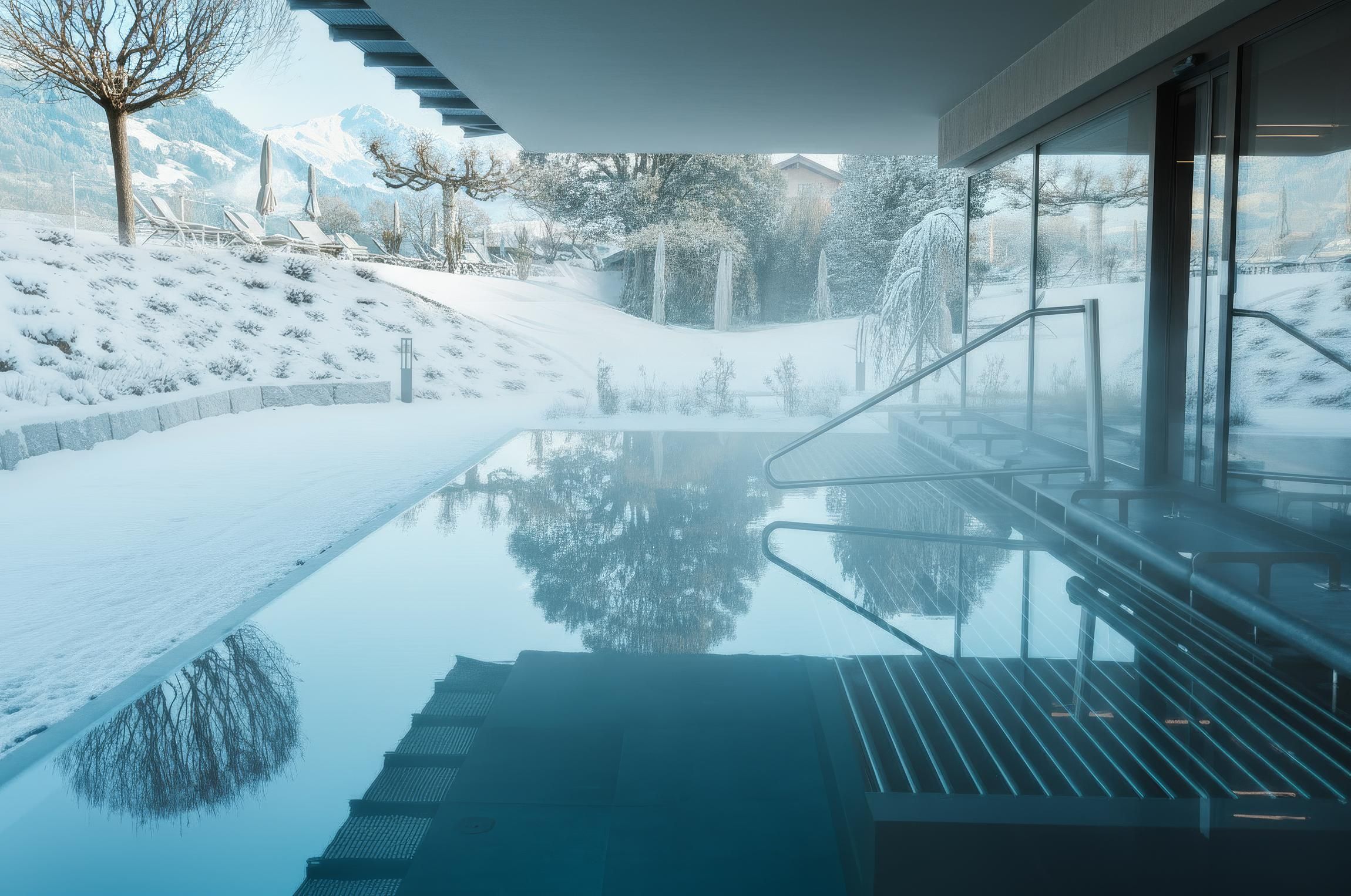 A modern indoor pool with calm water and a view of a snowy landscape. The atmosphere is relaxed and inviting.