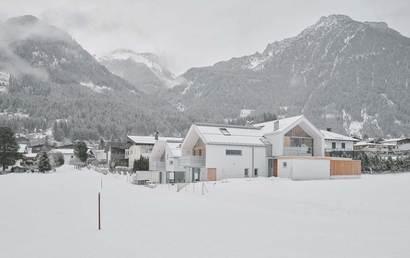 A modern house in a snowy landscape. Majestic mountains can be seen in the background.
