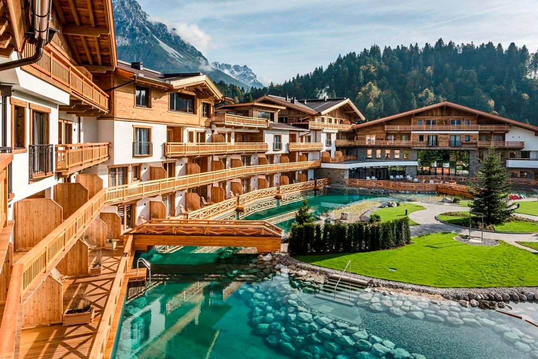 A beautiful resort with wooden balconies and a clear water pool. Surrounded by lush meadows and mountains, the property exudes tranquility and relaxation.