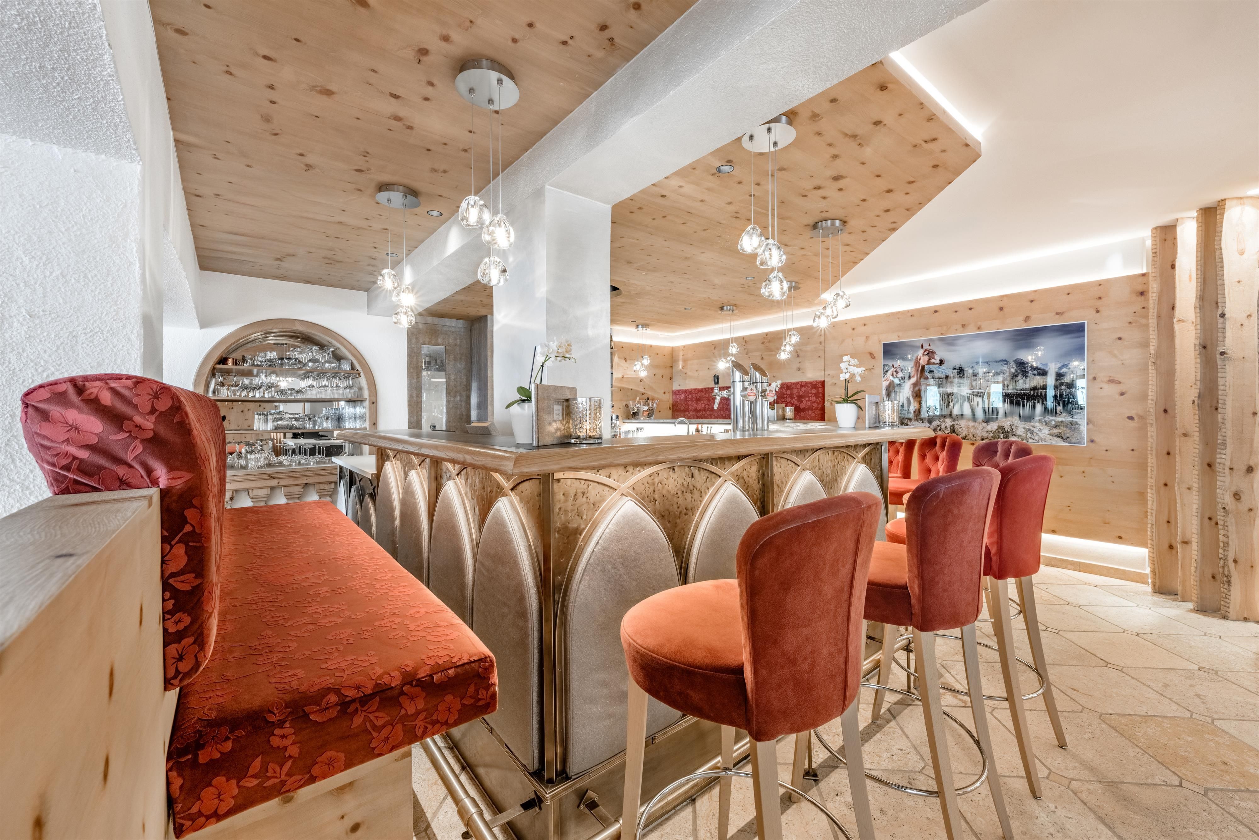 A stylish bar with elegant red chairs and a wooden ceiling. Chemical and cozy lighting creates an inviting atmosphere.