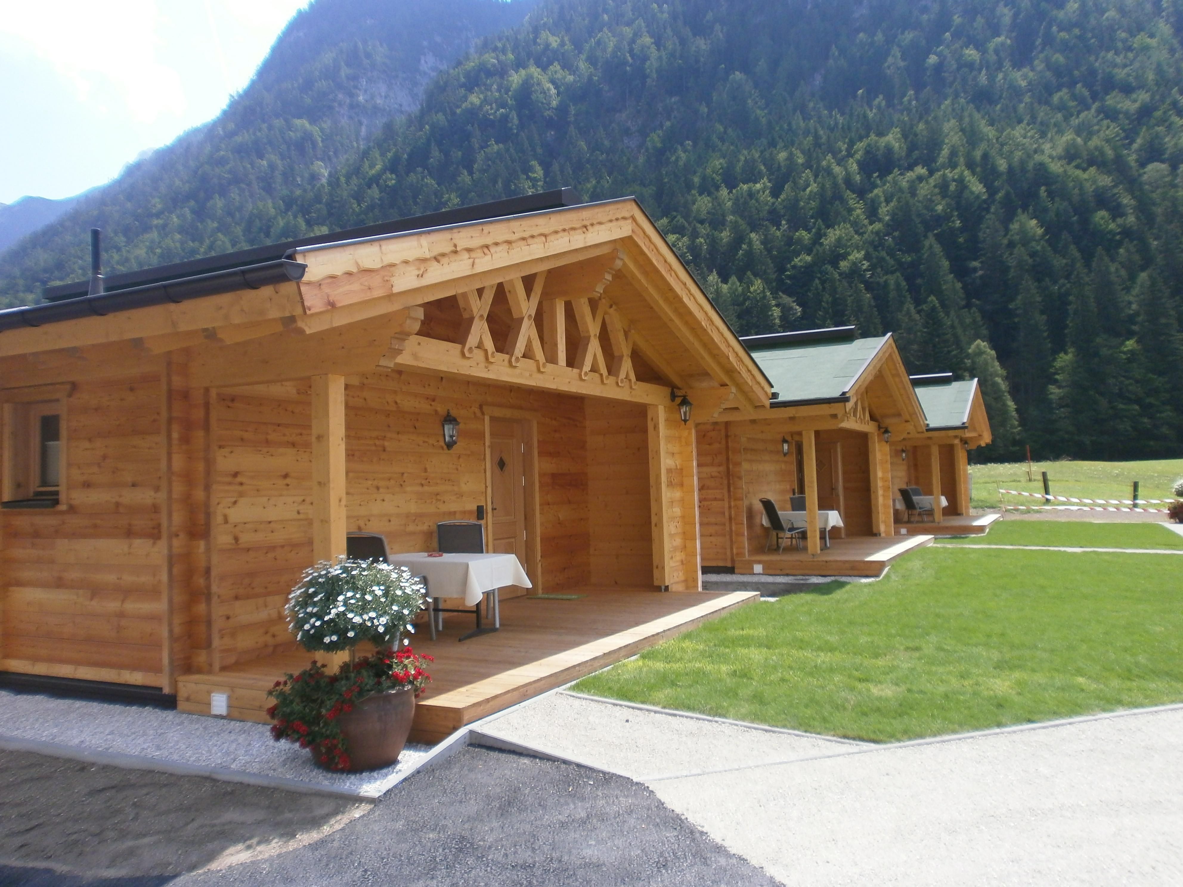 Cozy wooden cabins in a picturesque setting. The cabins are surrounded by green spaces and mountains.