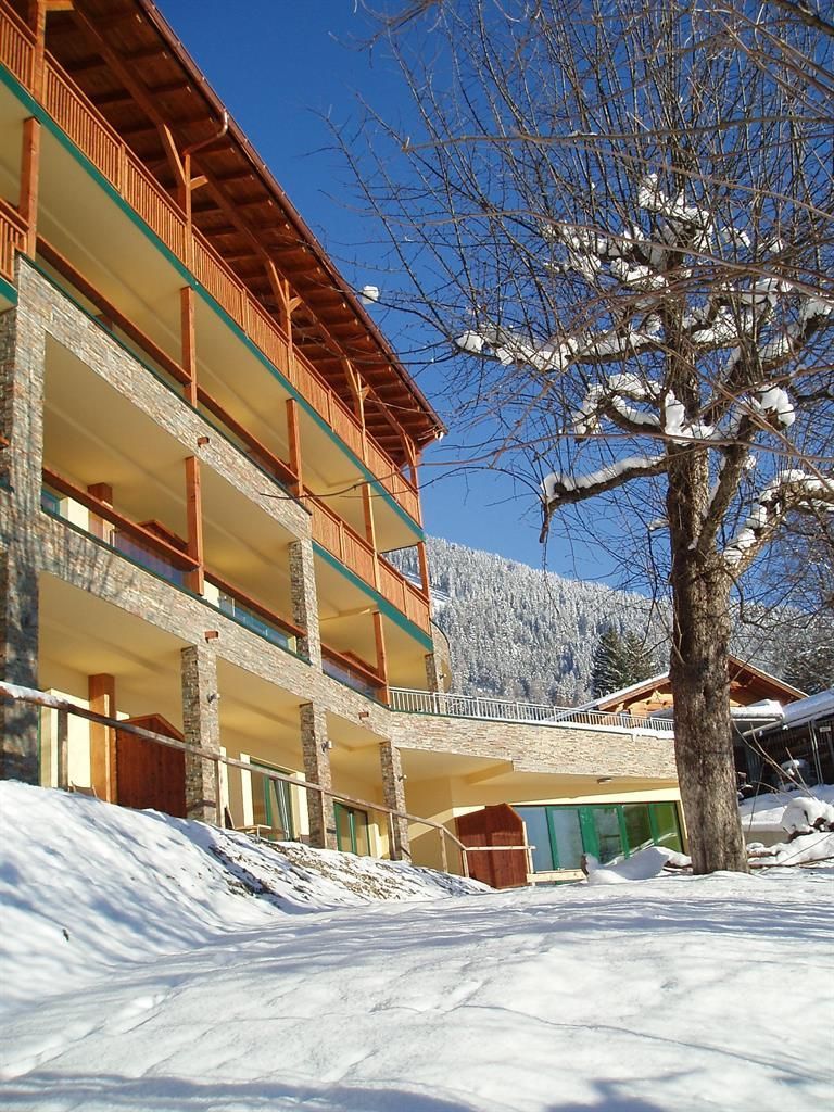A modern building in a snowy landscape. In the background, snow-covered mountains and a clear blue sky can be seen.