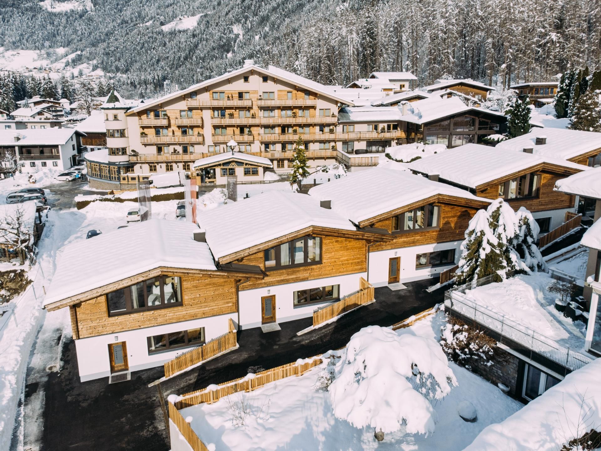 A picturesque winter village with snow-covered cottages and a hotel amidst the mountains. The tranquil landscape conveys a cozy atmosphere.