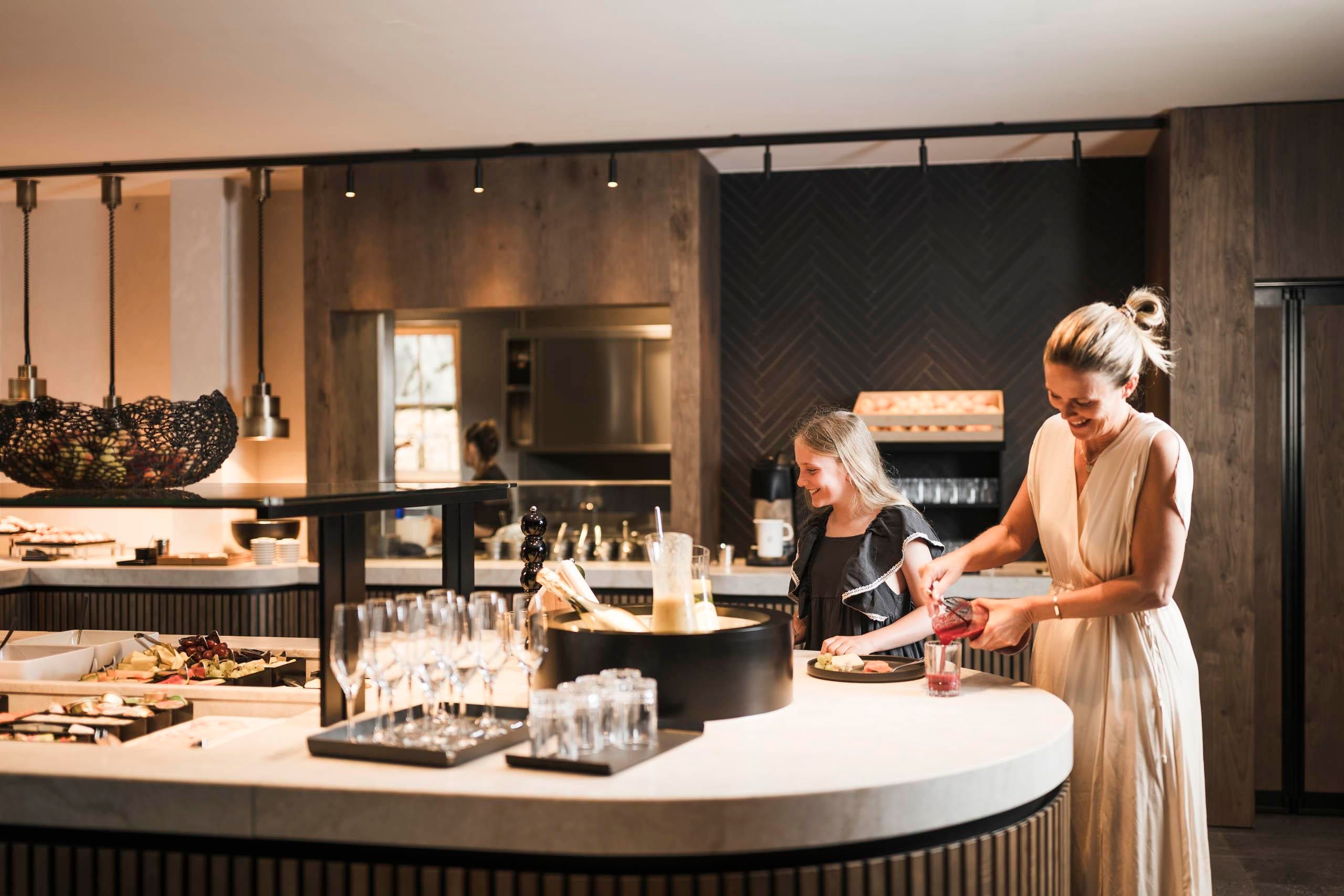 A modern kitchen with a round countertop. A woman and a girl are preparing food and enjoying their time together.