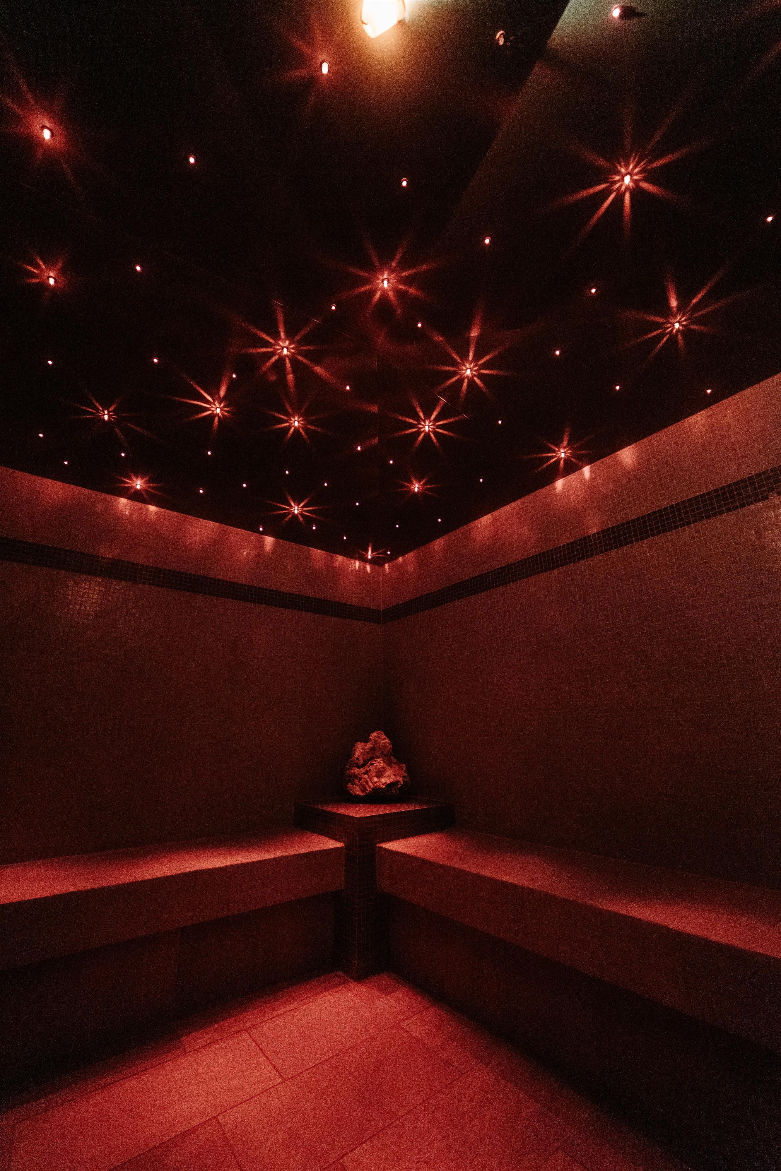 A relaxing room with red walls and soft lighting. In the center stands a statue that creates a calm atmosphere.
