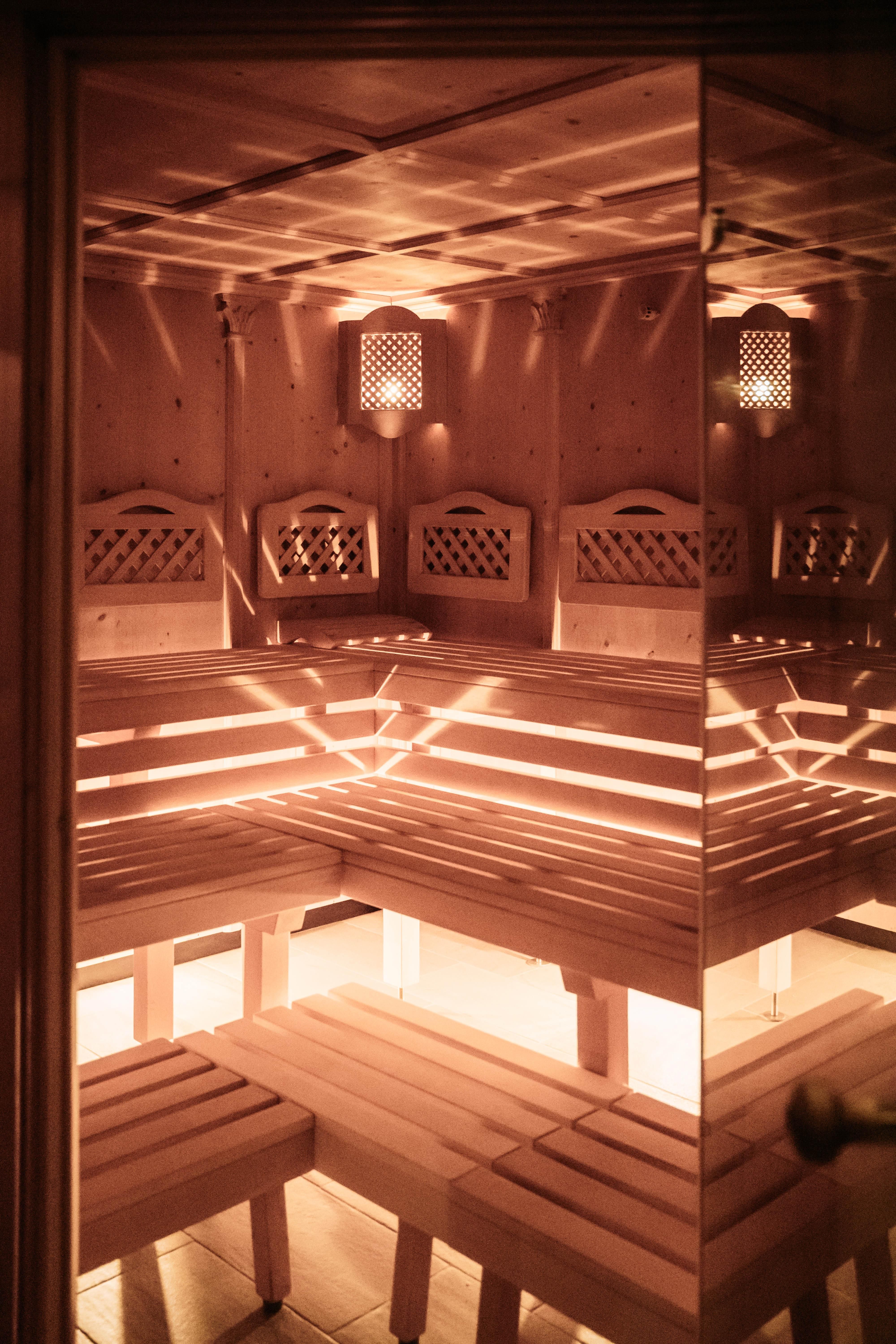 A cozy sauna with a wooden bench and soft lighting. The room radiates relaxation and warmth.