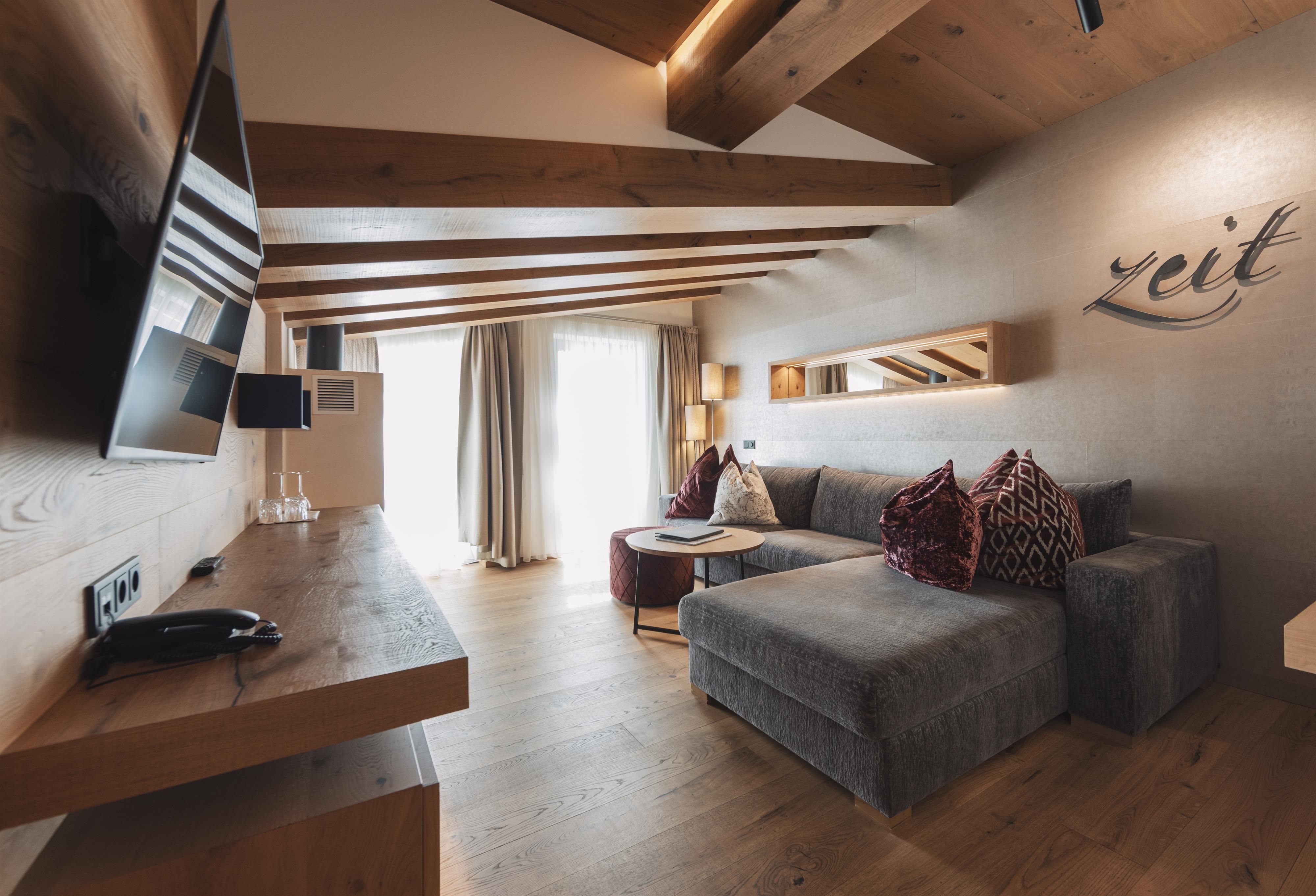 A modern living room with a wooden ceiling and a cozy sofa. The room is bright and inviting, with a large window that lets in light.