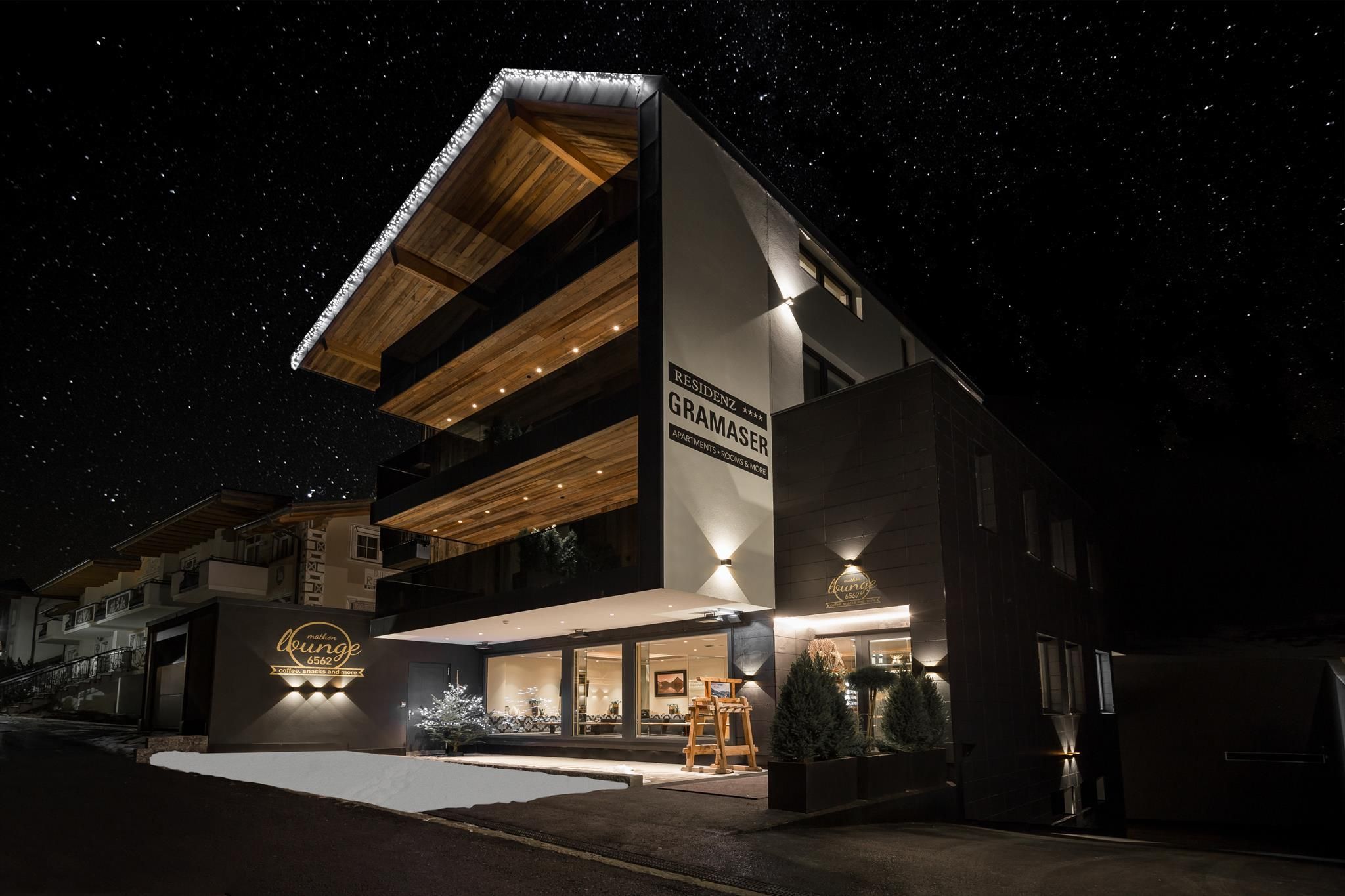 A modern building at night with illuminated balconies. The sky is clear and full of stars.