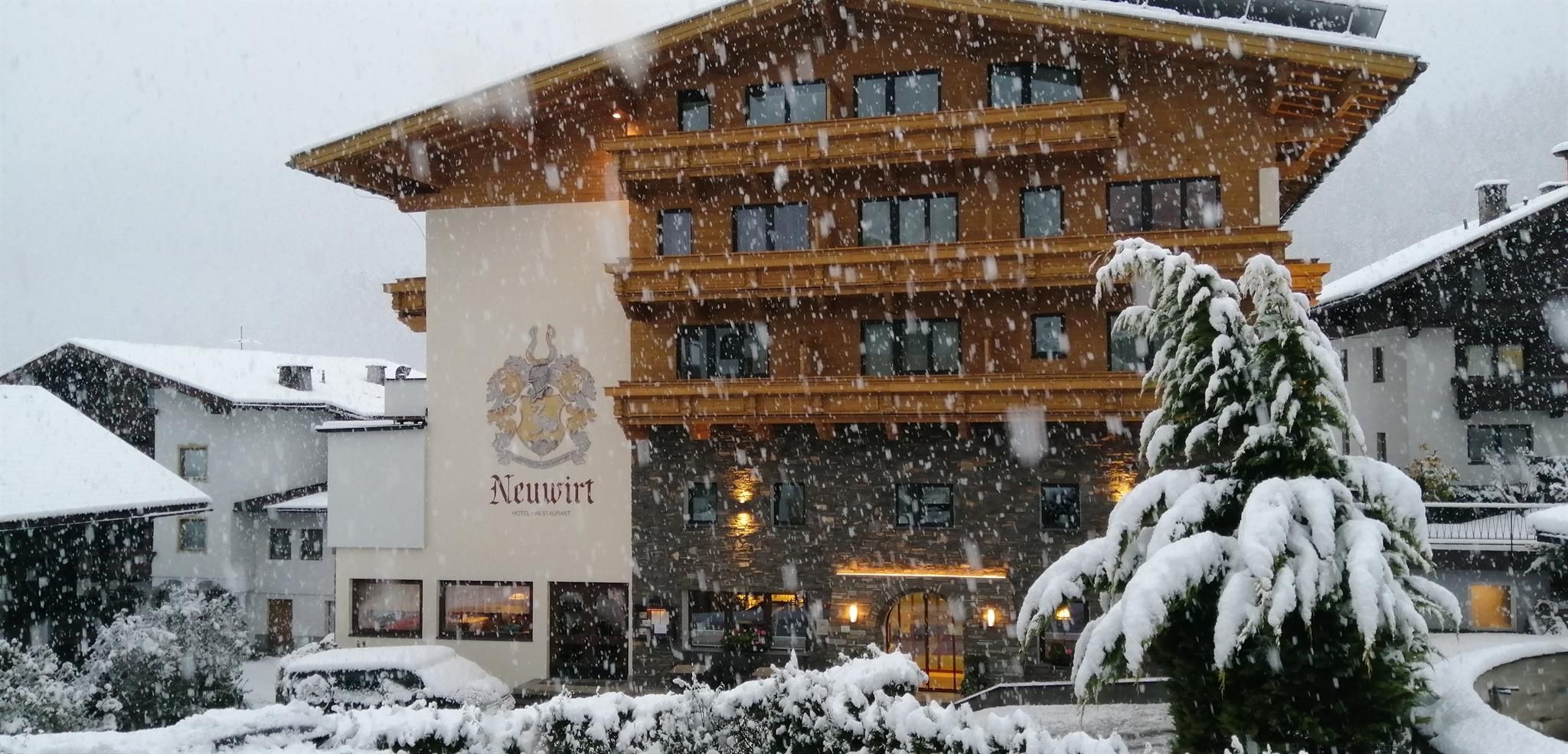 A picturesque hotel nestled in a snowy landscape. Large snowflakes fall on the cozy facade and the surrounding trees.