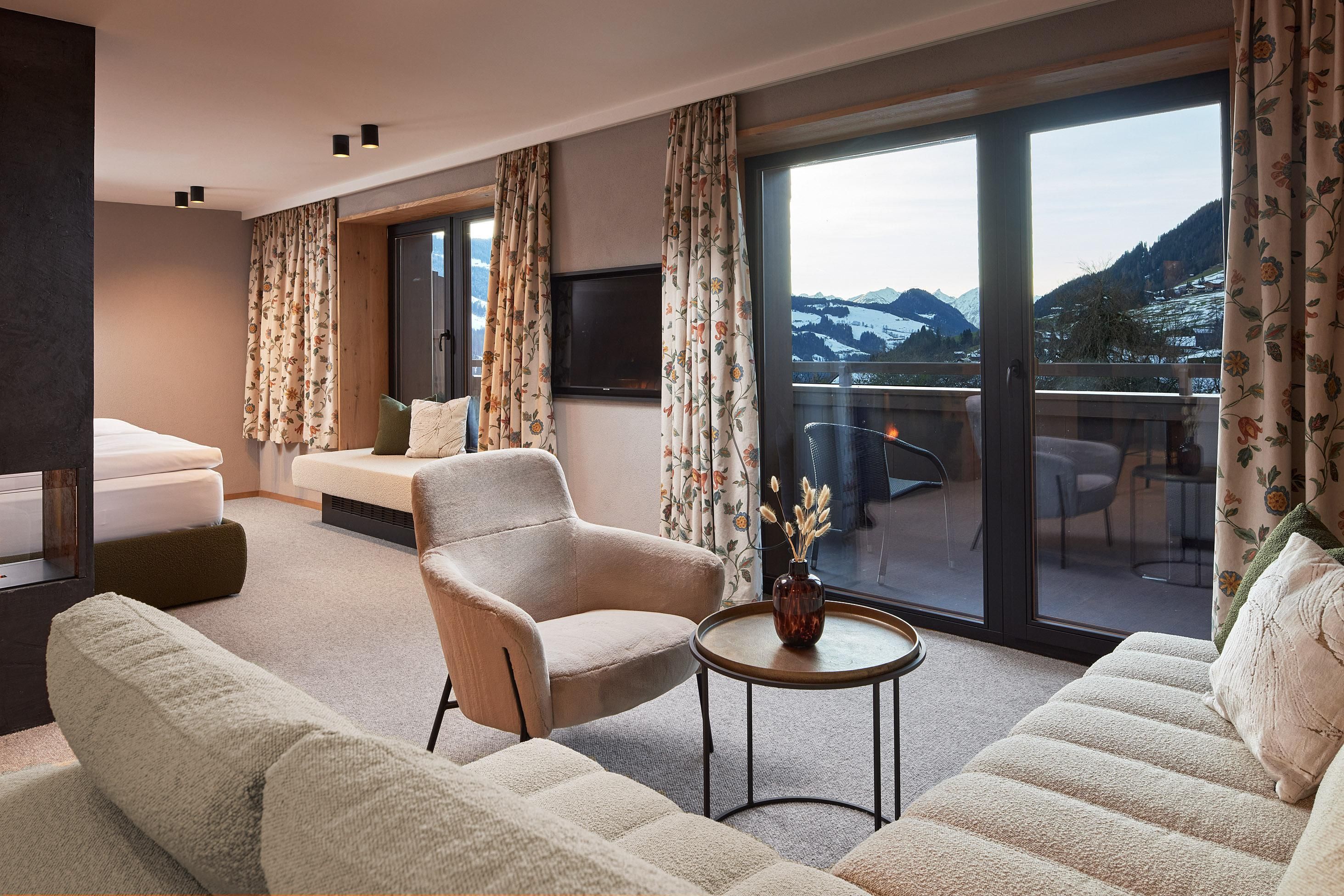 A modern hotel room with a cozy living area.
Large windows offer a view of the mountains and plenty of daylight.