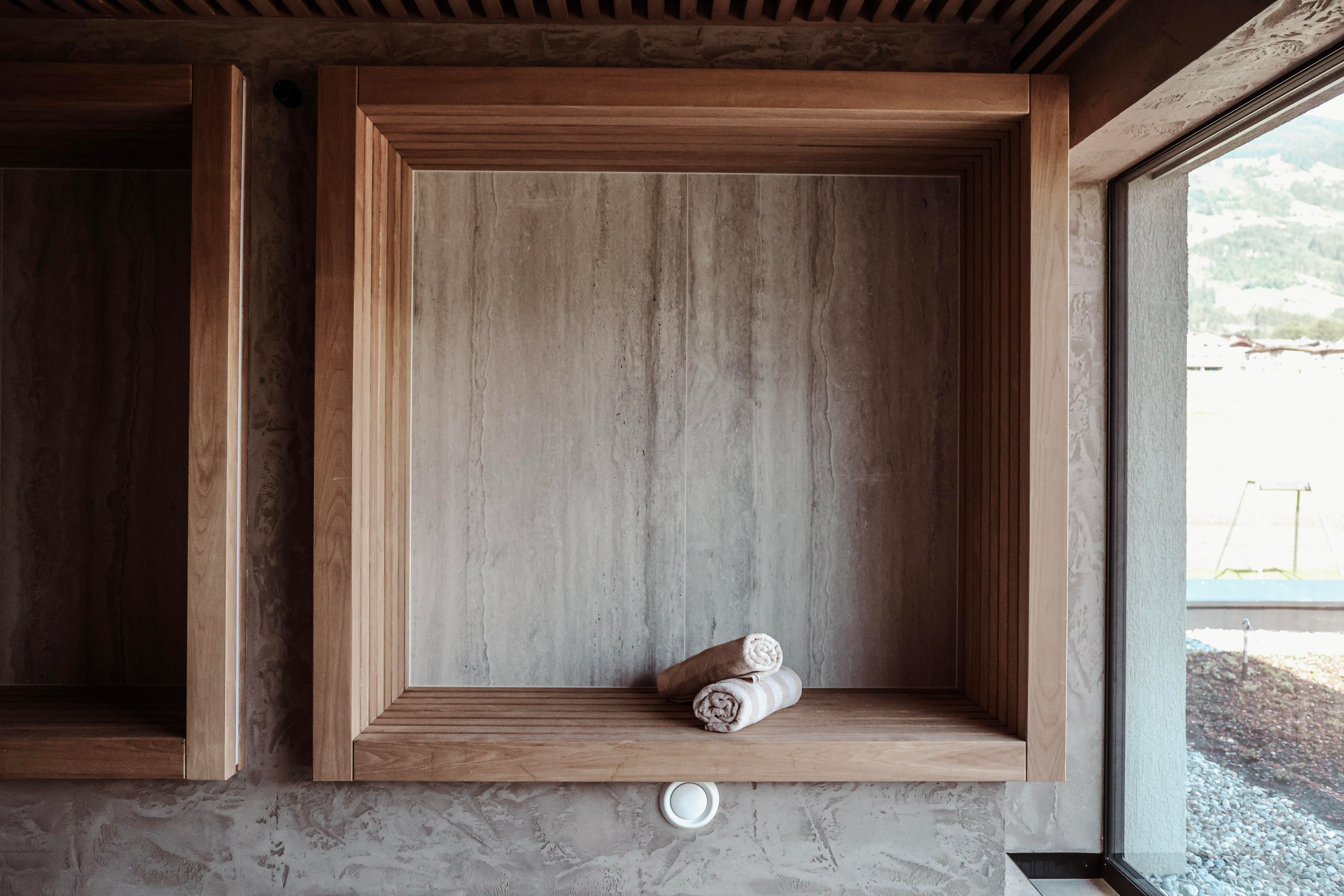 A minimalist shelf with a wooden frame and two folded towels. The background is in soft, neutral colors.