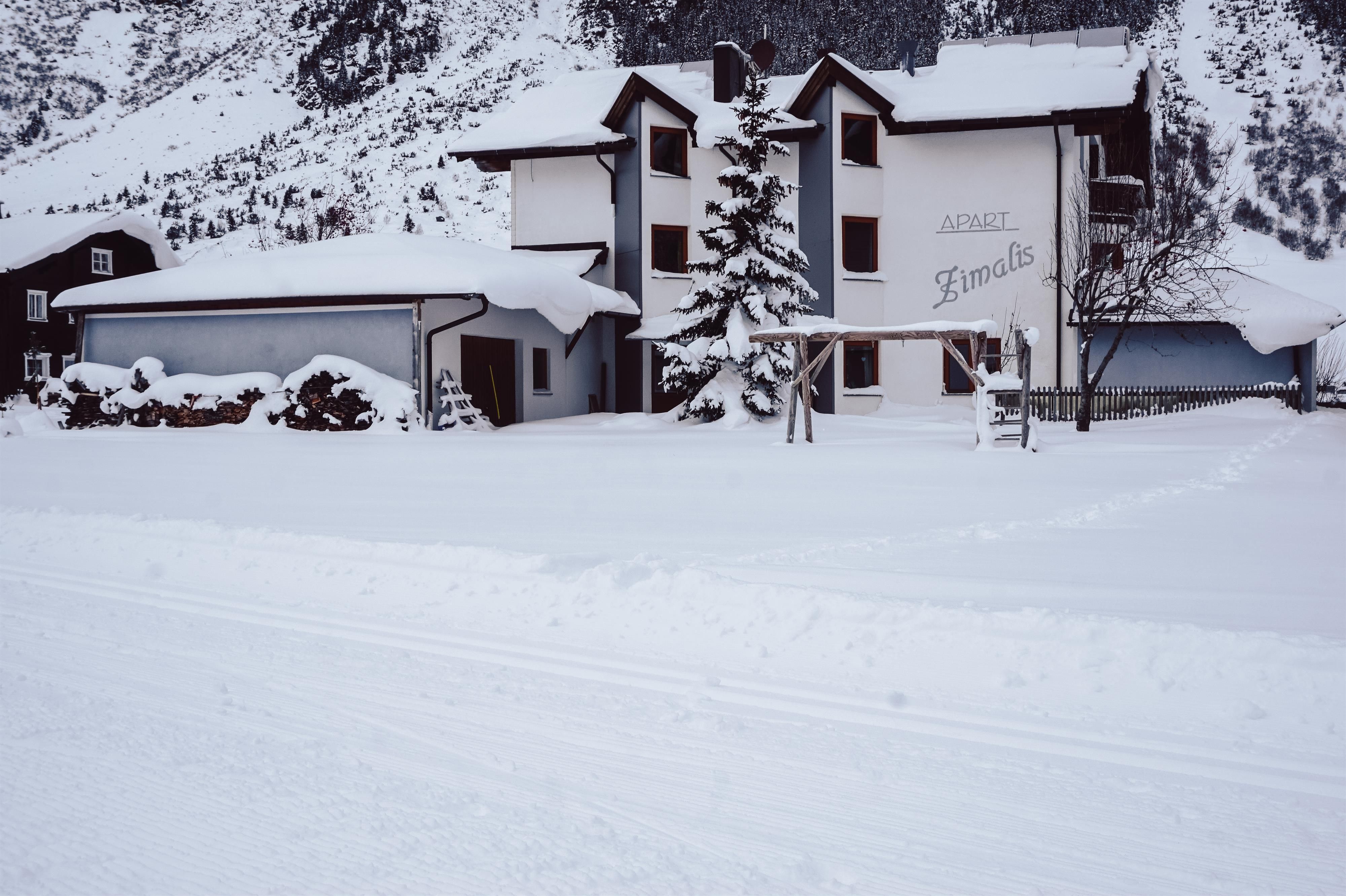 A snow-covered house surrounded by mountains. Winter conjures a calm, peaceful atmosphere.