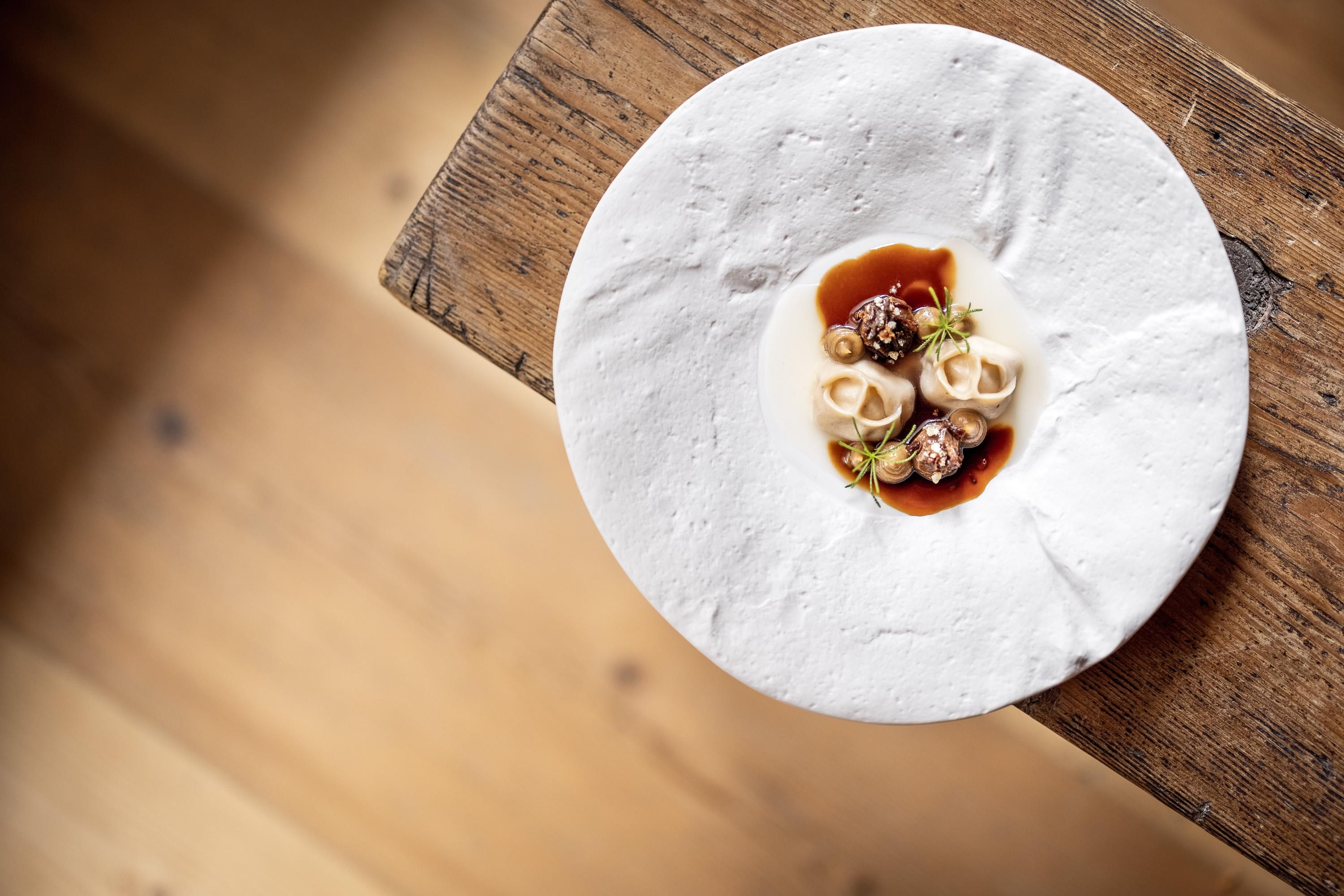 An artistically arranged plate with a small portion of food. The plate is placed on a wooden table.