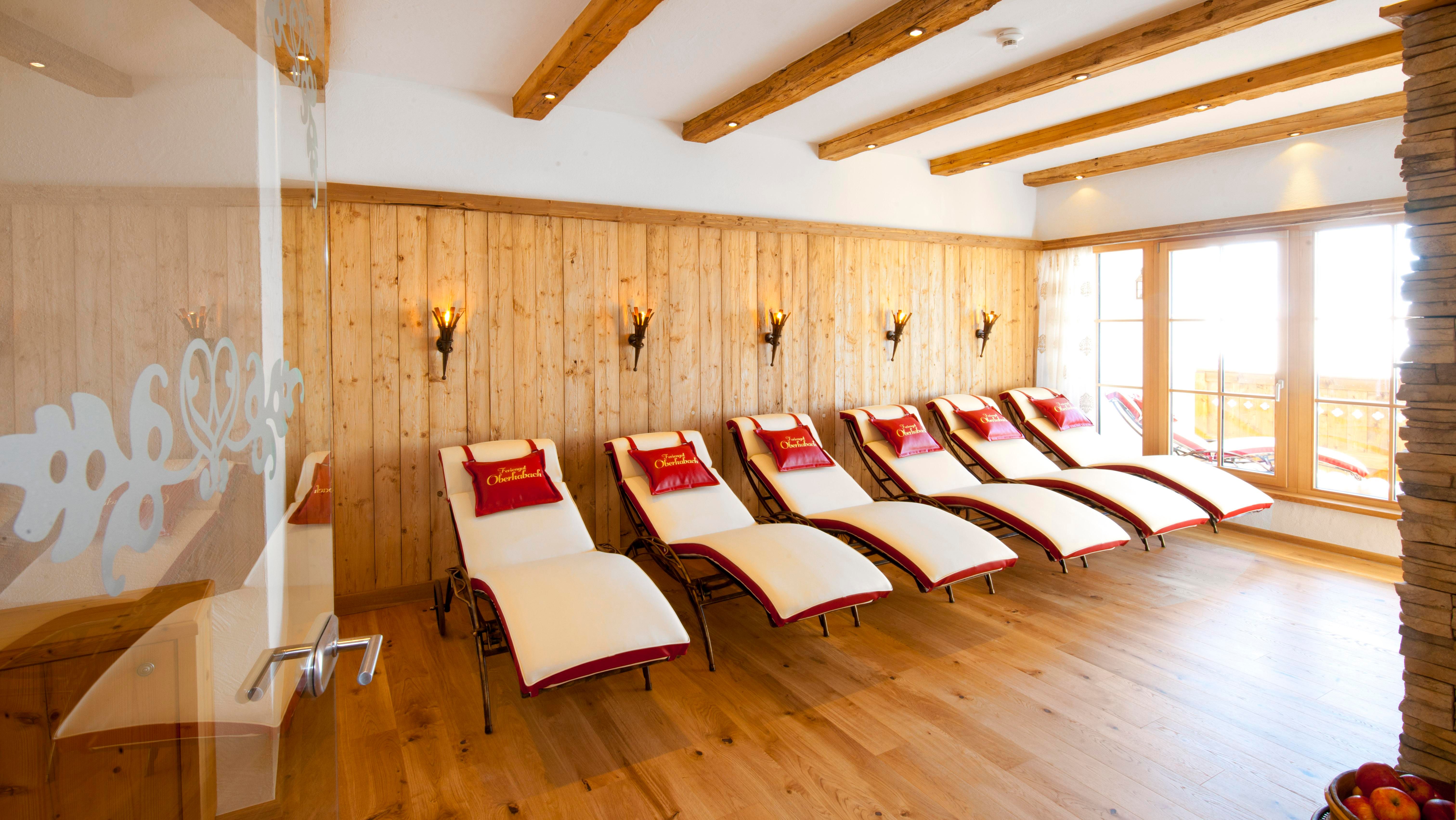A stylish relaxation room with several loungers and light wood decor. Large windows provide plenty of daylight and a relaxing atmosphere.