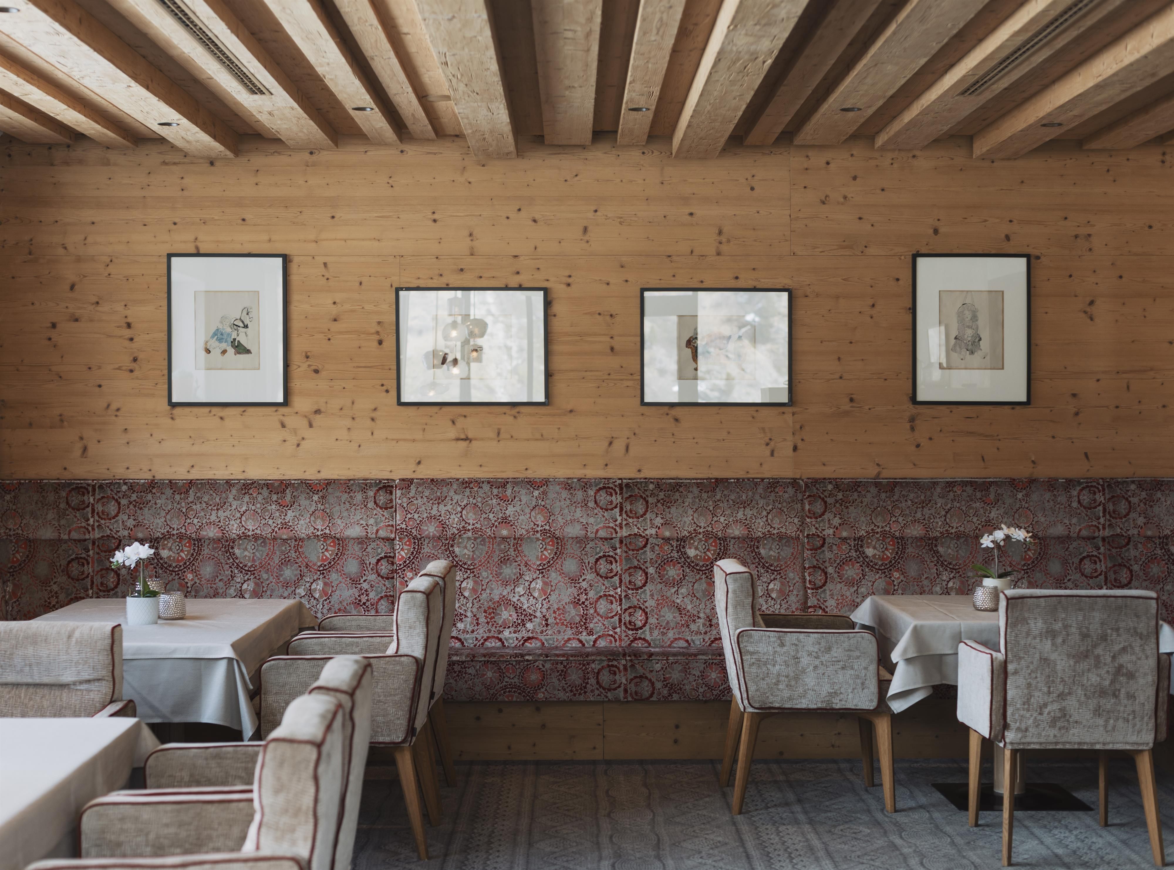 A cozy restaurant with wooden paneling and elegant furniture. Framed pictures hang on the walls, creating a stylish atmosphere.