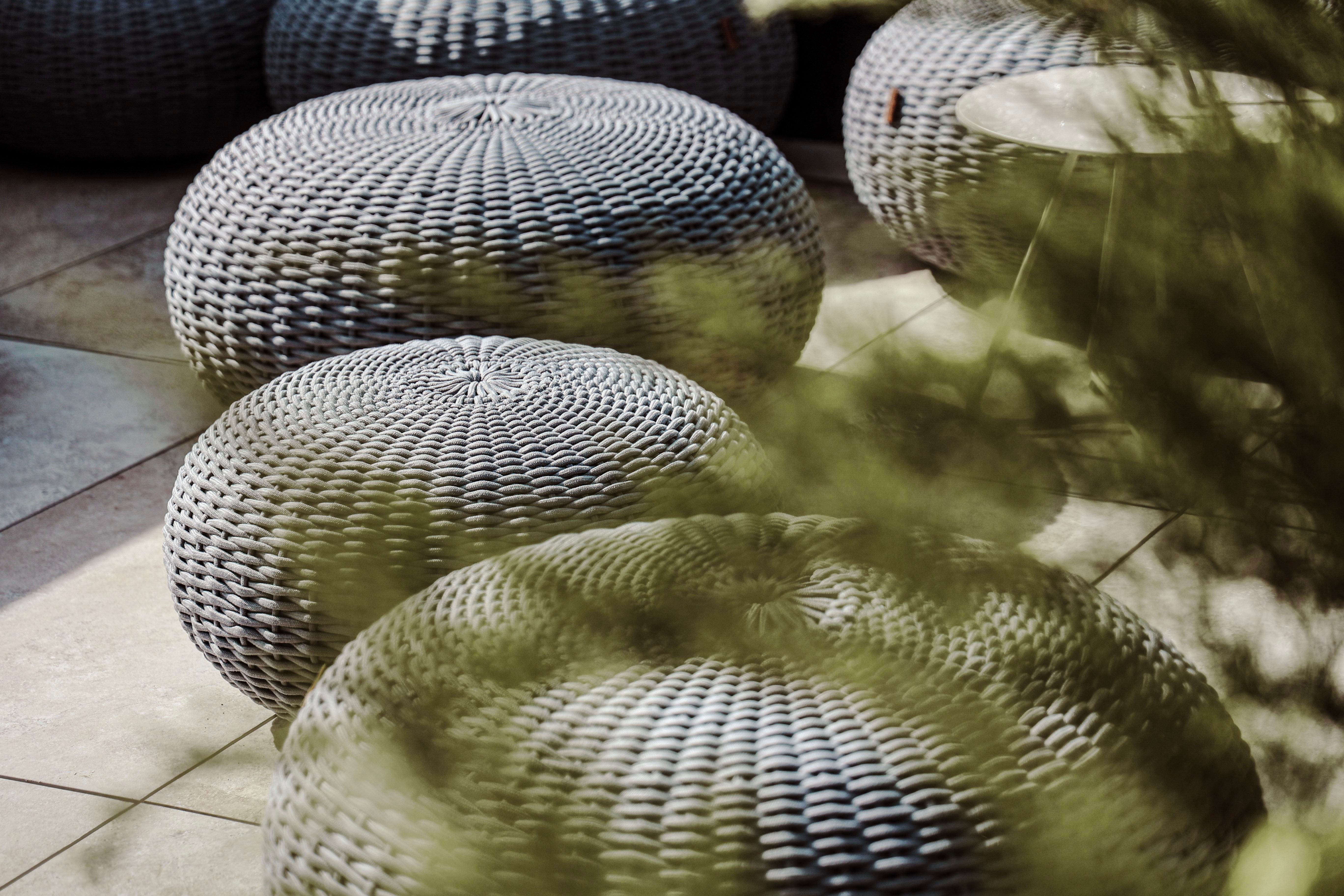 An area with round, gray seating cushions made of woven material. In the background, more similar cushions can be seen.