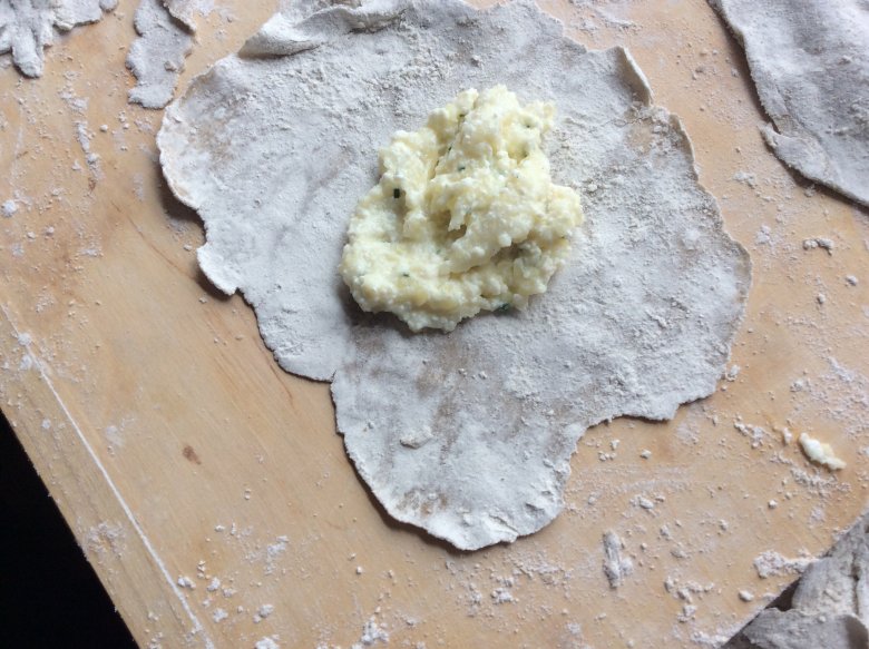 Een beetje aardappel-kaasbrij op de stukjes deeg doen – niet te veel, want anders loopt de brij bij het bakken uit de Krapfen.