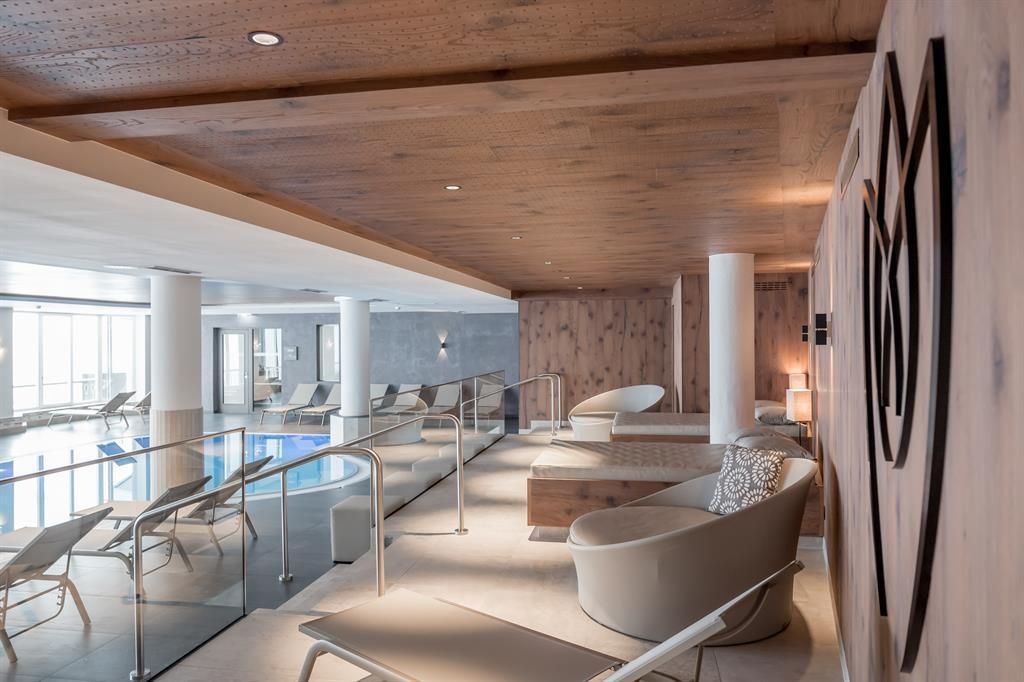 An elegant wellness area with modern loungers and an indoor pool. The warm wood details create a relaxed atmosphere.
