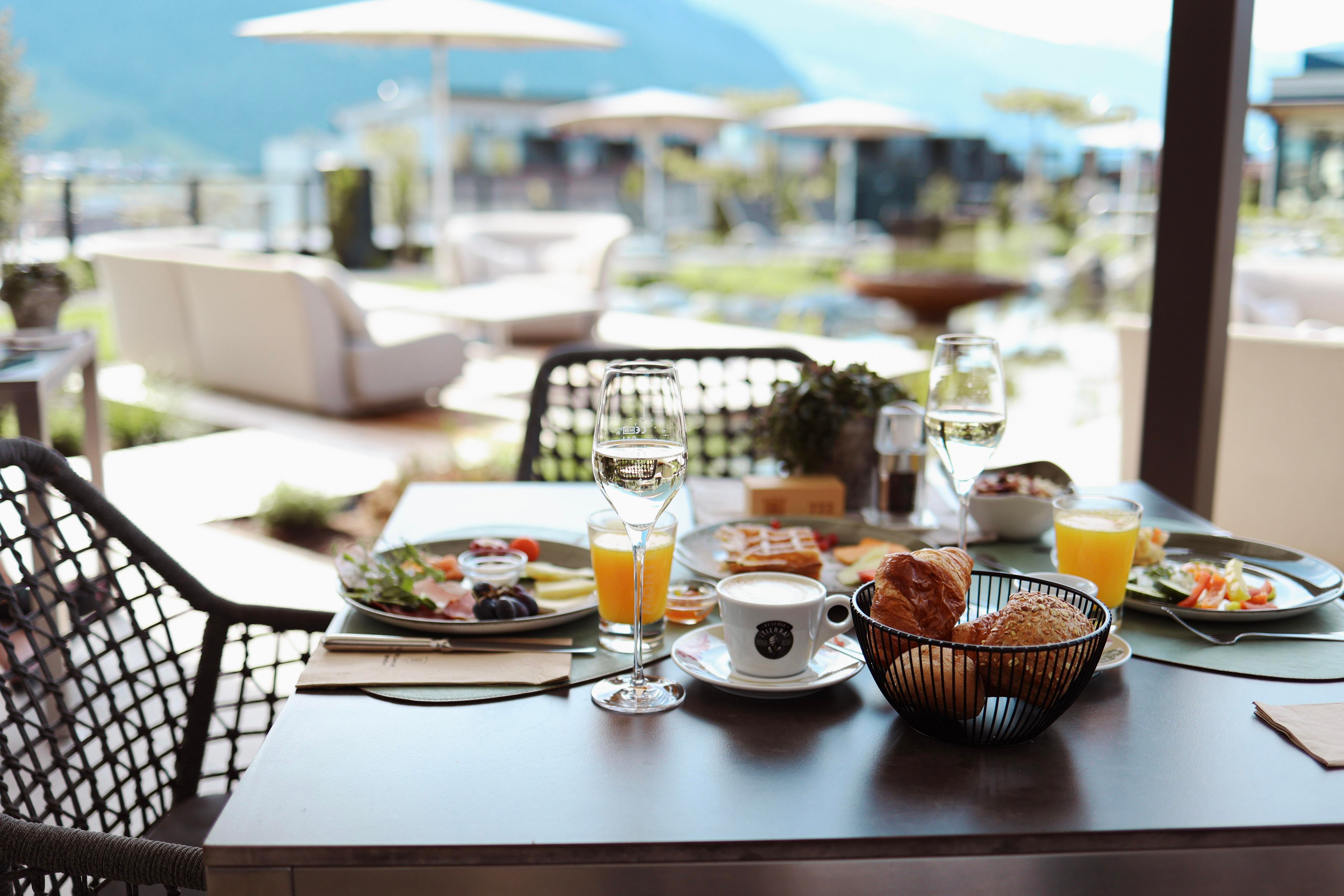 A set table on a terrace overlooking nature. A delicious breakfast with fruit, croissants, and drinks awaits the guests.
