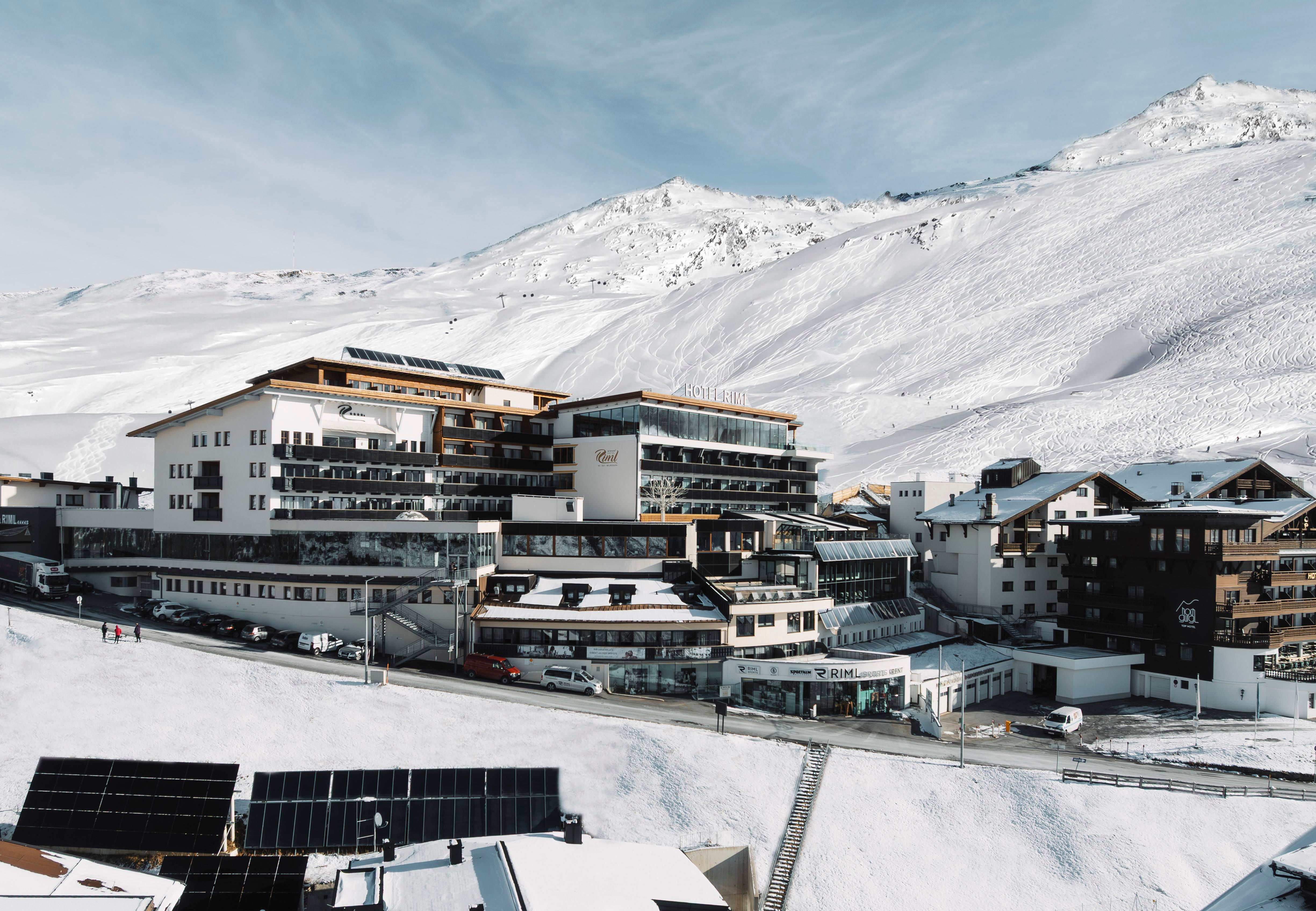A modern hotel in a snow-covered mountain landscape. The surroundings are calm and inviting, surrounded by snowy peaks.
