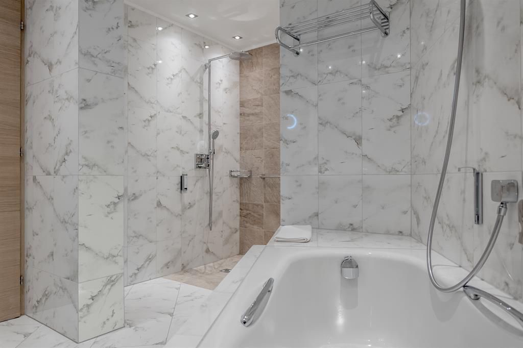 A modern bathroom with marbled walls and elegant bathroom fixtures. The shower is separate, and the ambiance feels bright and inviting.