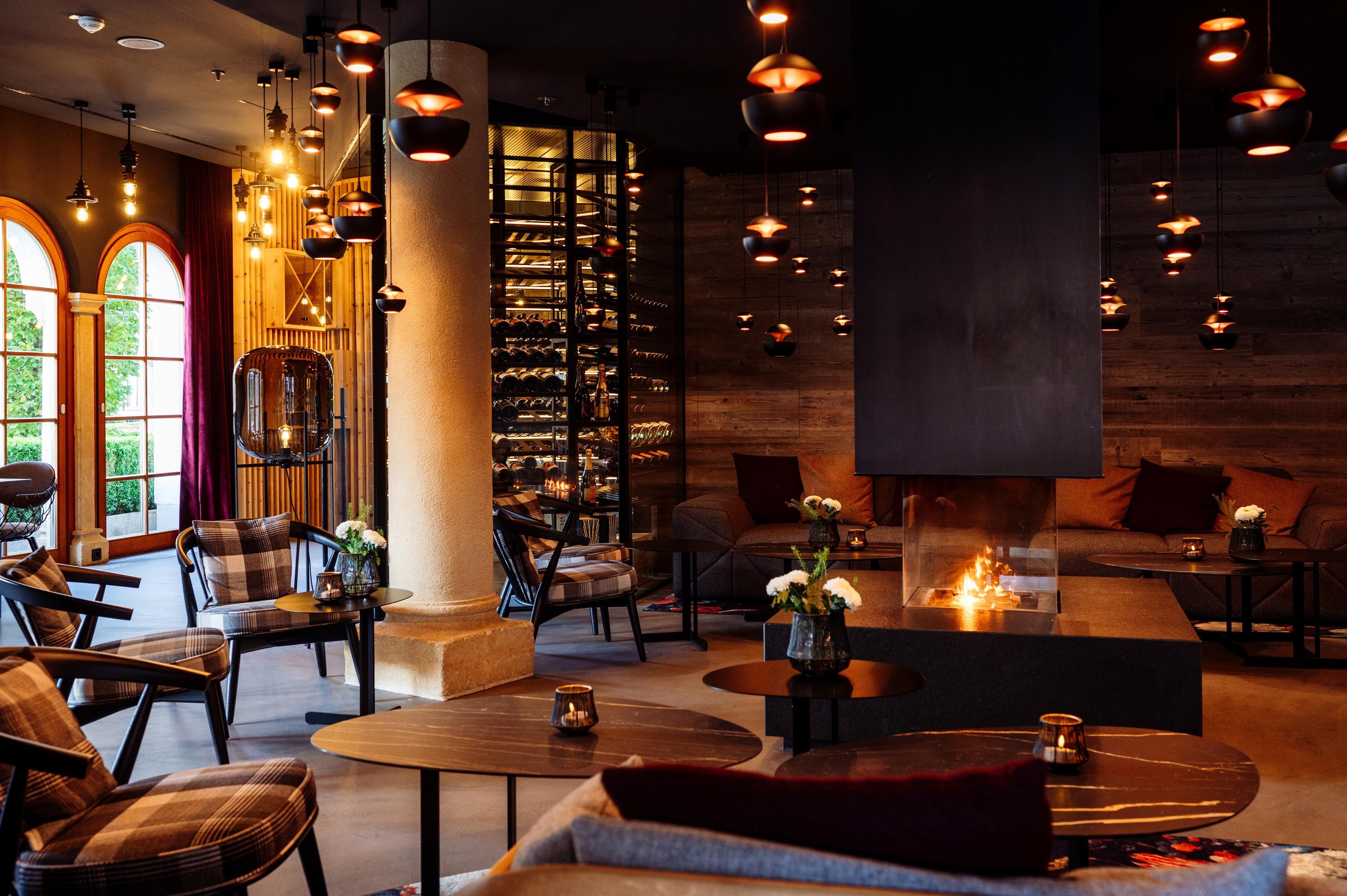 A cozy interior with stylish furniture and soft lighting. The room features a fireplace and a wine collection.