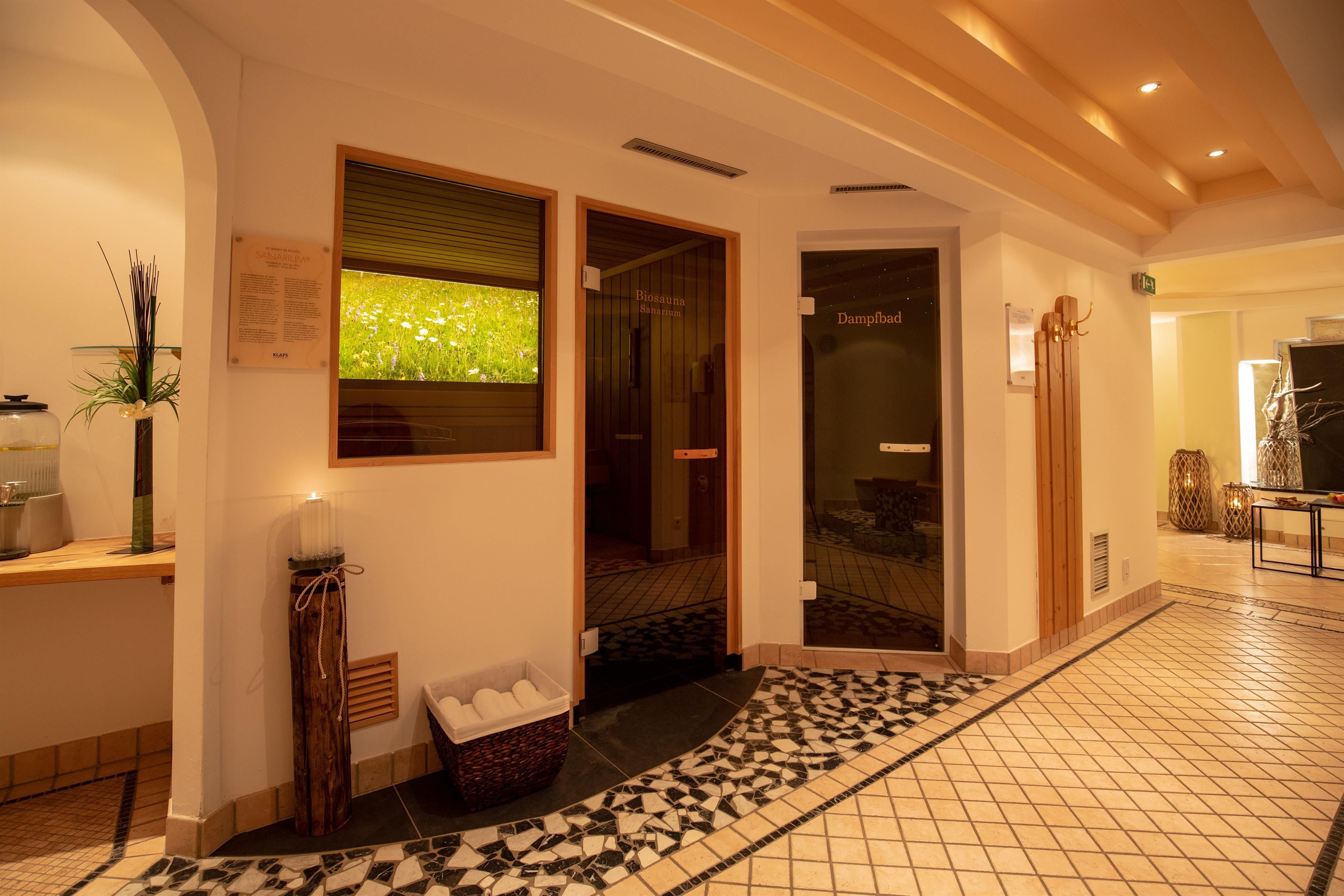 An inviting wellness area with two doors and a modern, minimalist design. The floor is adorned with decorative tiles and there are some plants for decoration.