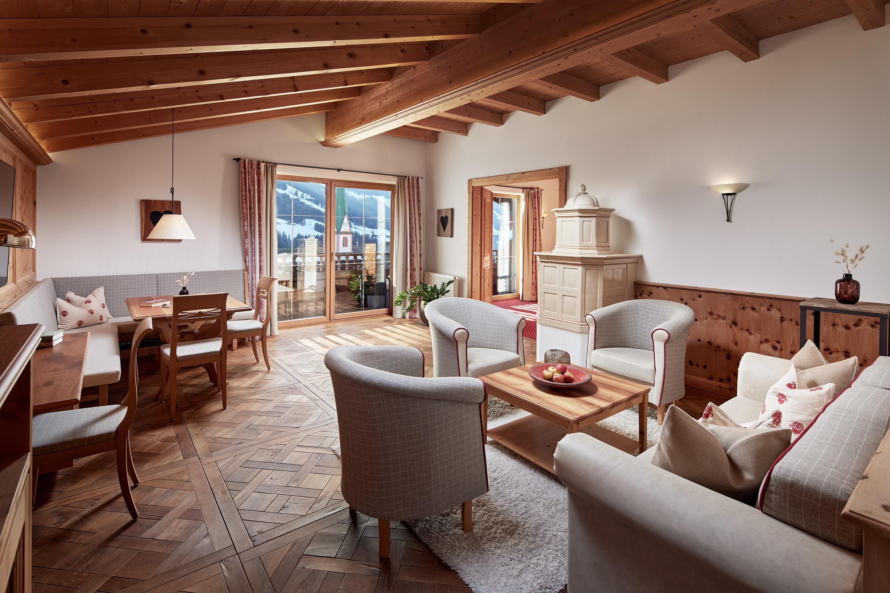 A cozy living room with wooden ceilings and modern furniture. Large windows provide a beautiful view of the surroundings.