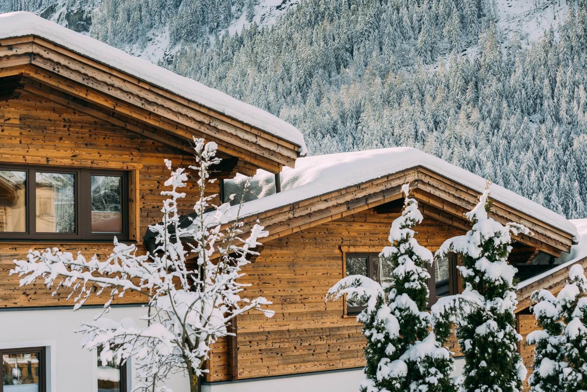 Snow-covered wooden houses in a winter mountain landscape. The surroundings are quiet and picturesque.