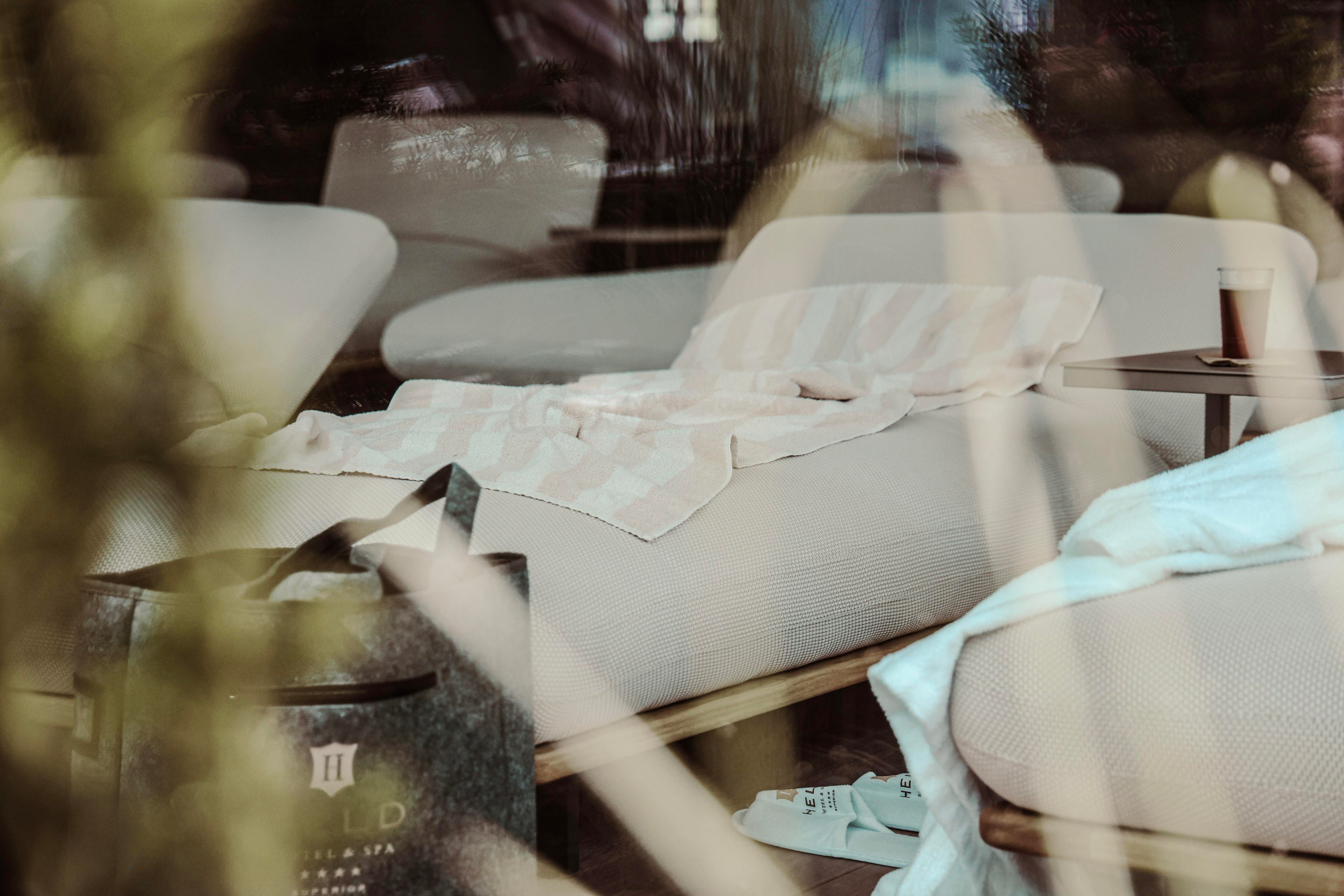 A cozy living environment with a beige sofa and a striped blanket. On the table is a cup of coffee and a black bag lies next to it.