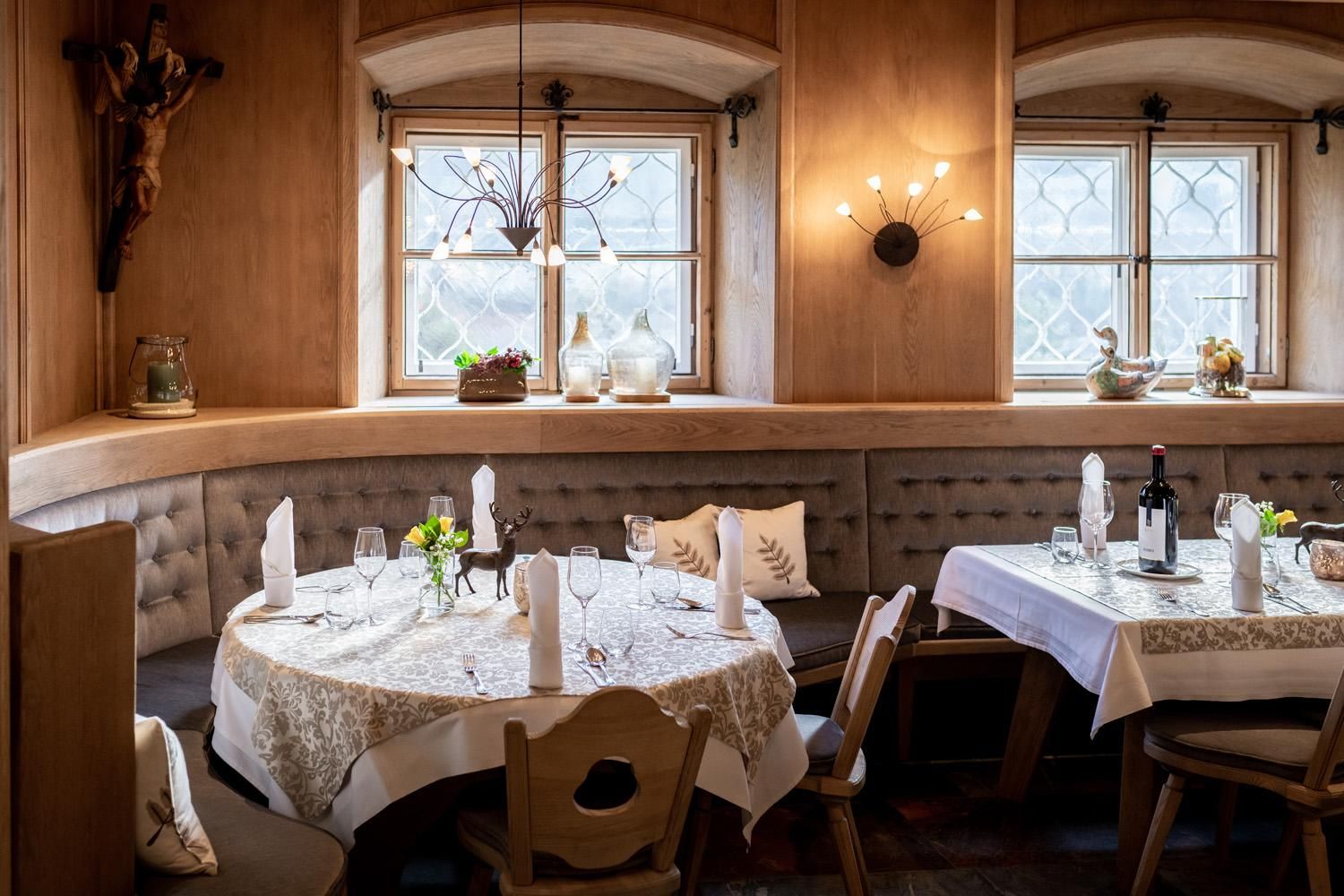 A cozy restaurant with wooden interiors and elegant tables. The windows let in plenty of light and the atmosphere is inviting.