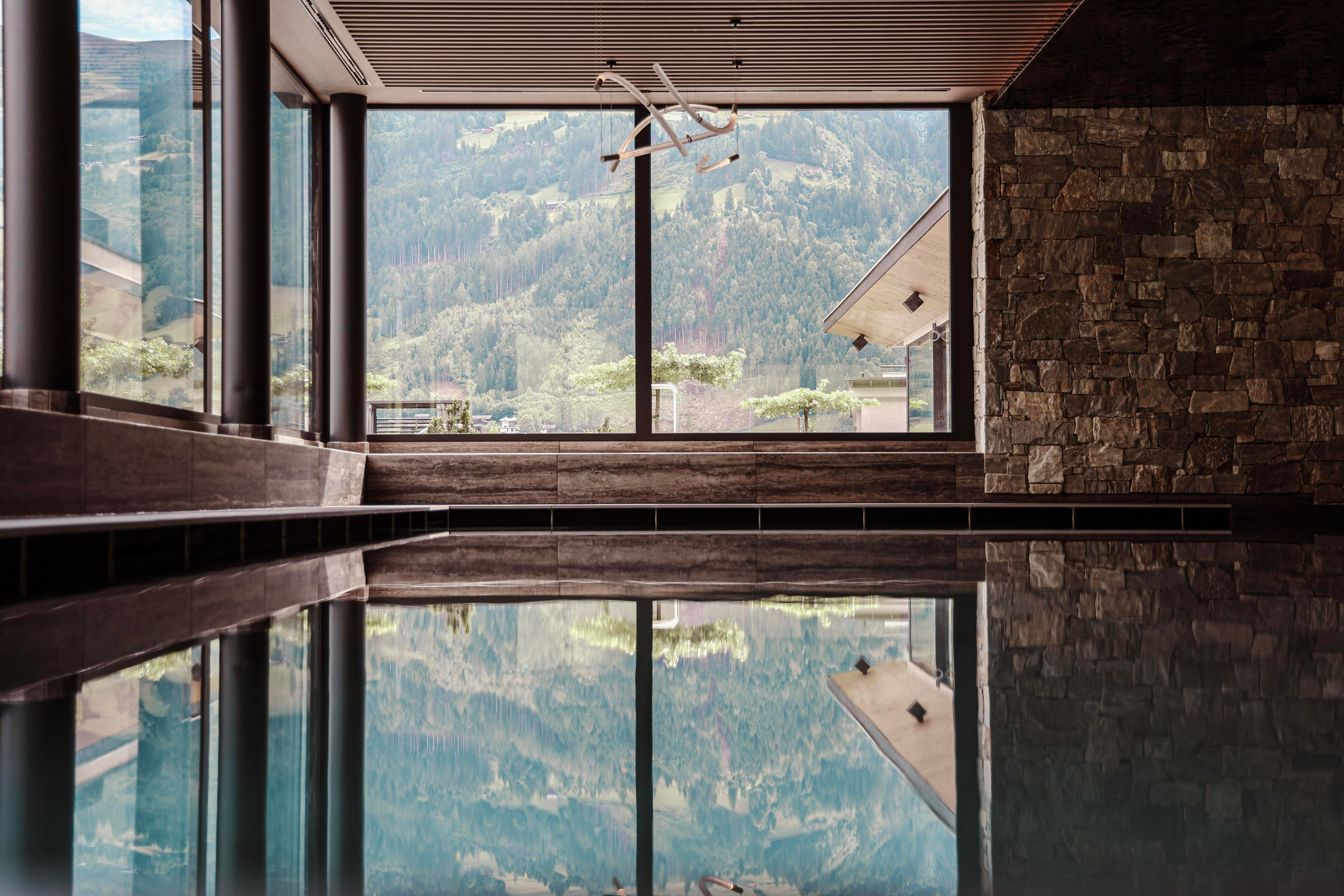 A modern wellness area with large windows and a view of the mountains. The floor reflects the calm water.