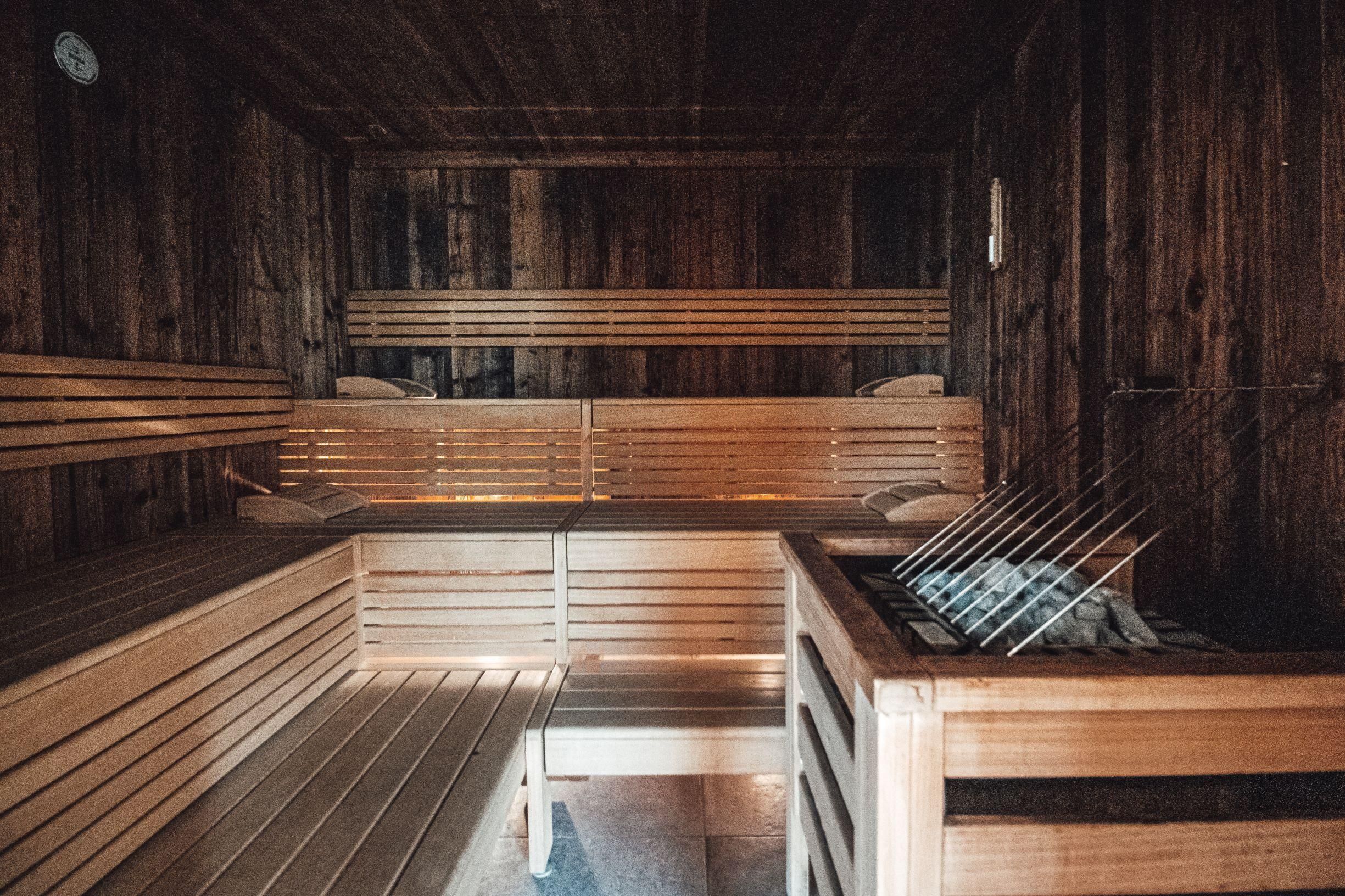 A bright sauna with wooden benches and a sauna stove. The walls are also made of wood, creating a cozy atmosphere.