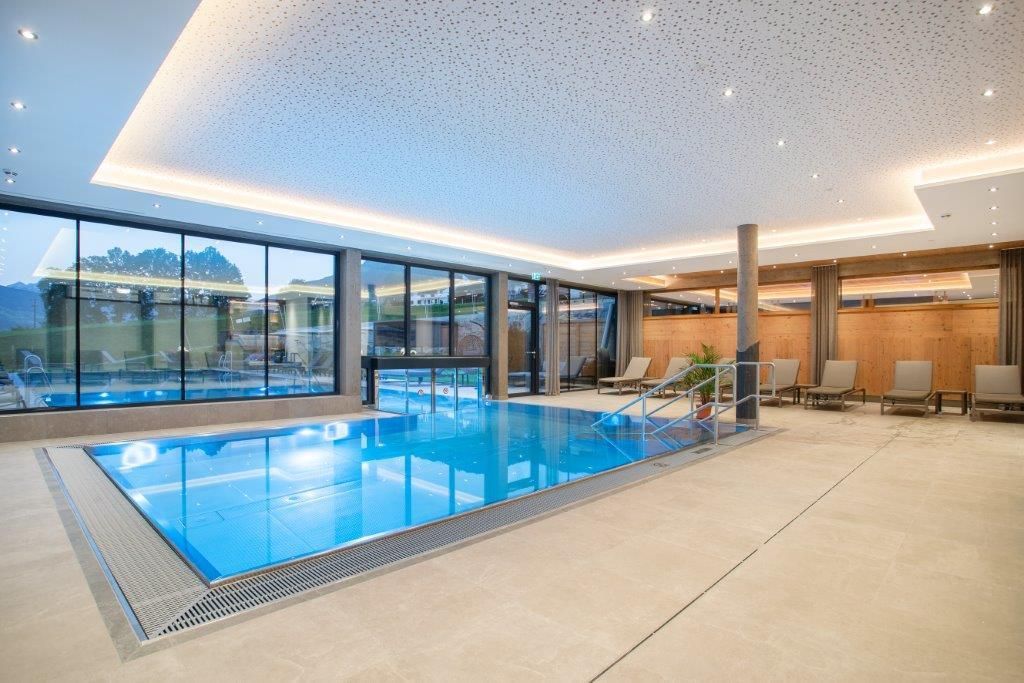 A modern indoor pool with large glass windows and a bright, elegant ambiance. Relaxed loungers and a tranquil atmosphere promote well-being.