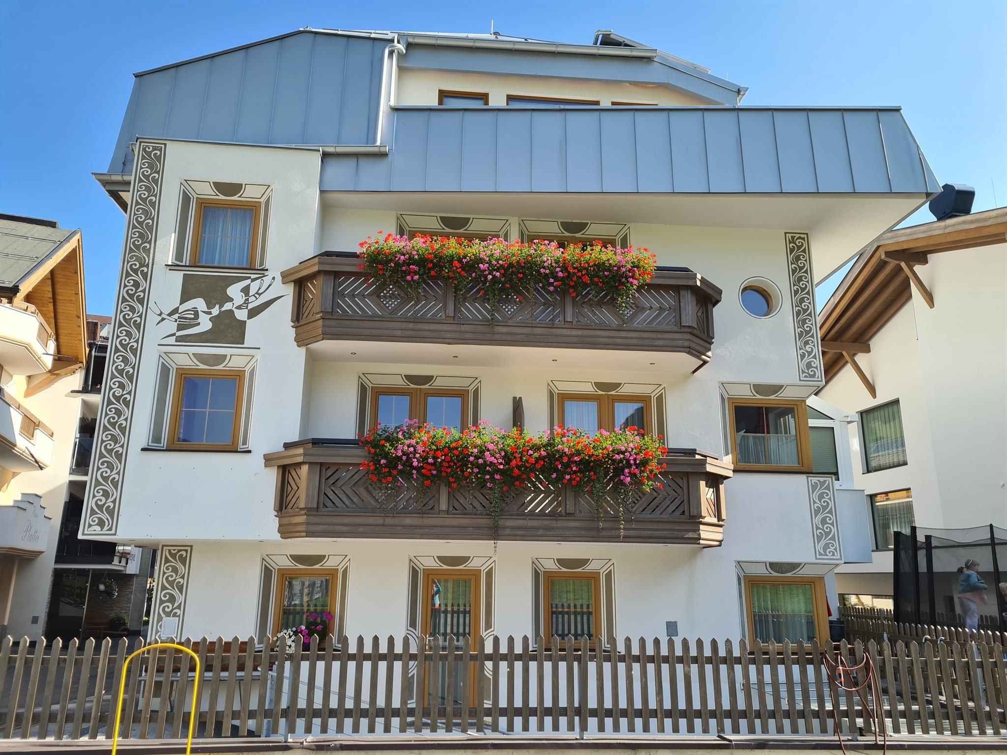 A beautiful house with balconies adorned with colorful flowers. The clear sky adds a cheerful atmosphere.