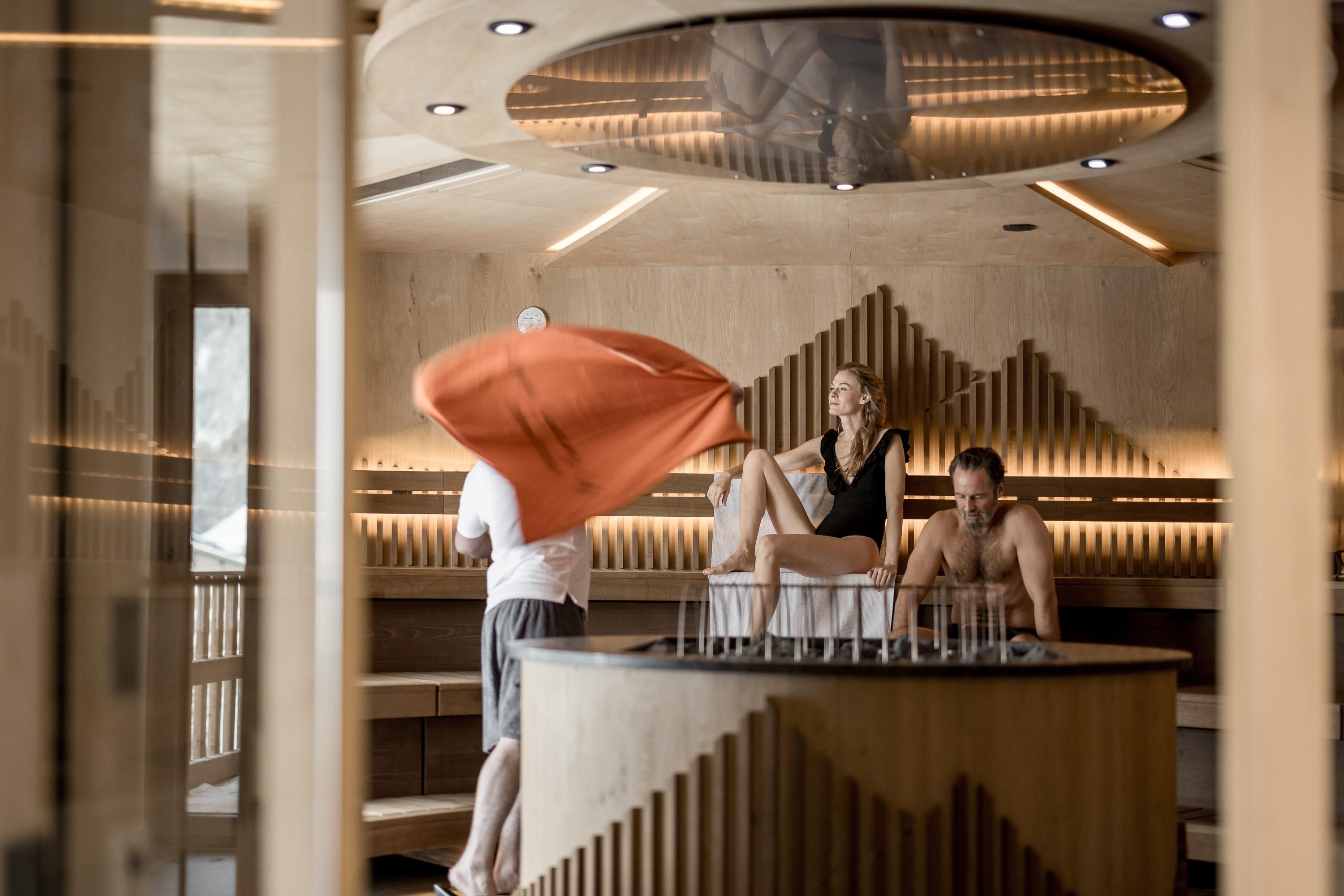 A modern spa with wooden decor and a round seating area. Three people are relaxing and enjoying the atmosphere.