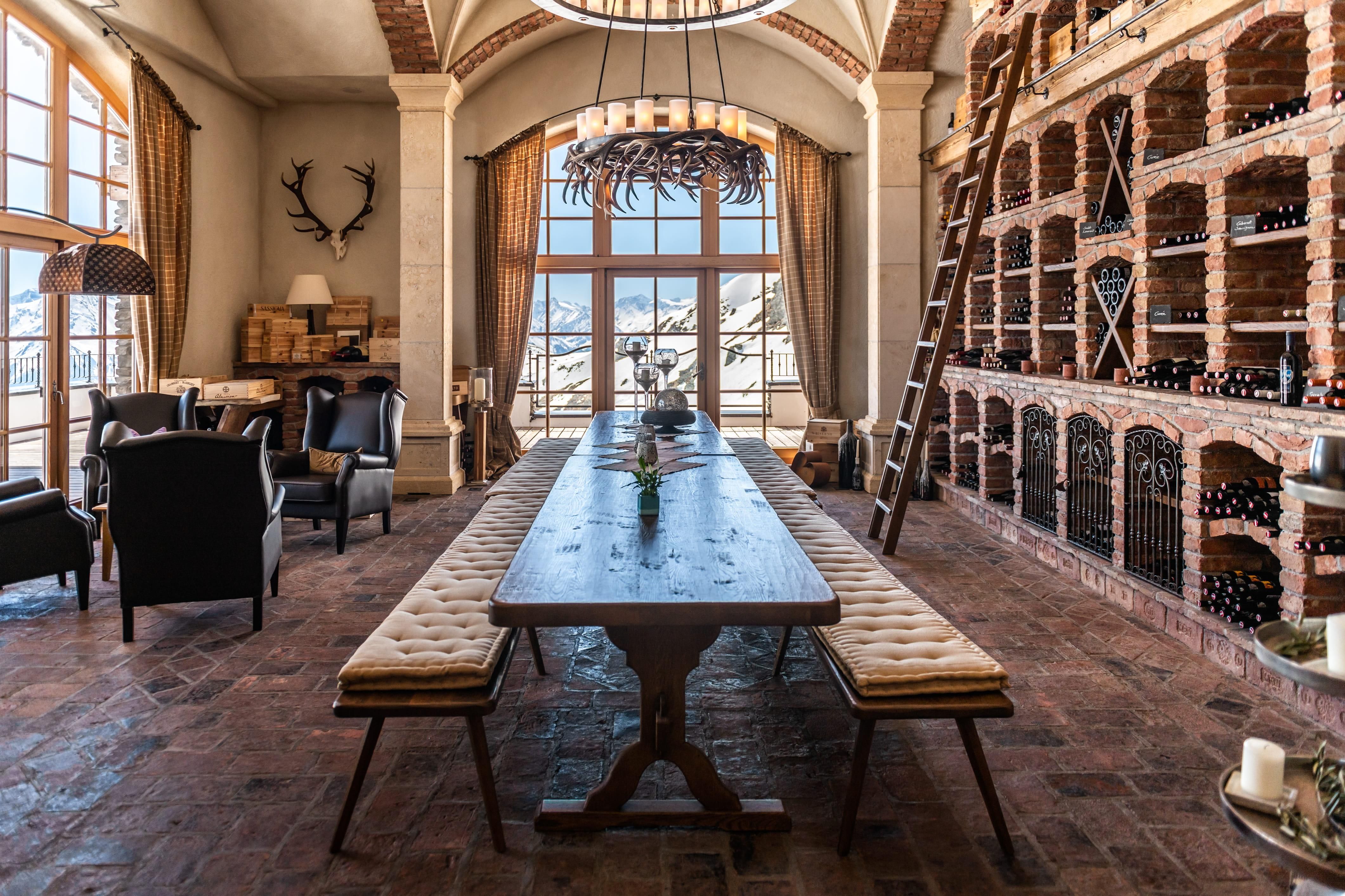 A stylish wine shop with a long wooden table and cozy chairs. In the background, there are wine shelves and large windows with a view.