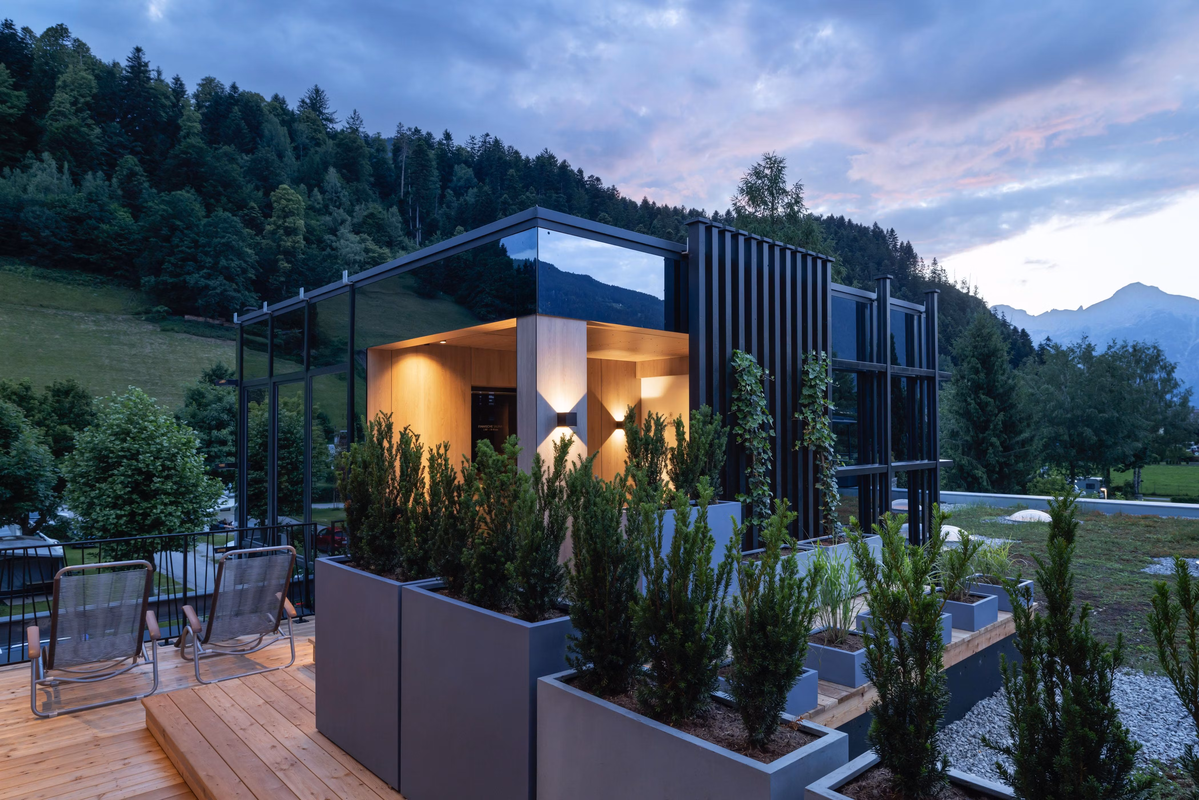 A modern house with large windows and modern architecture. Furthermore, there are garden areas with plants and trees in a landscaped environment.
