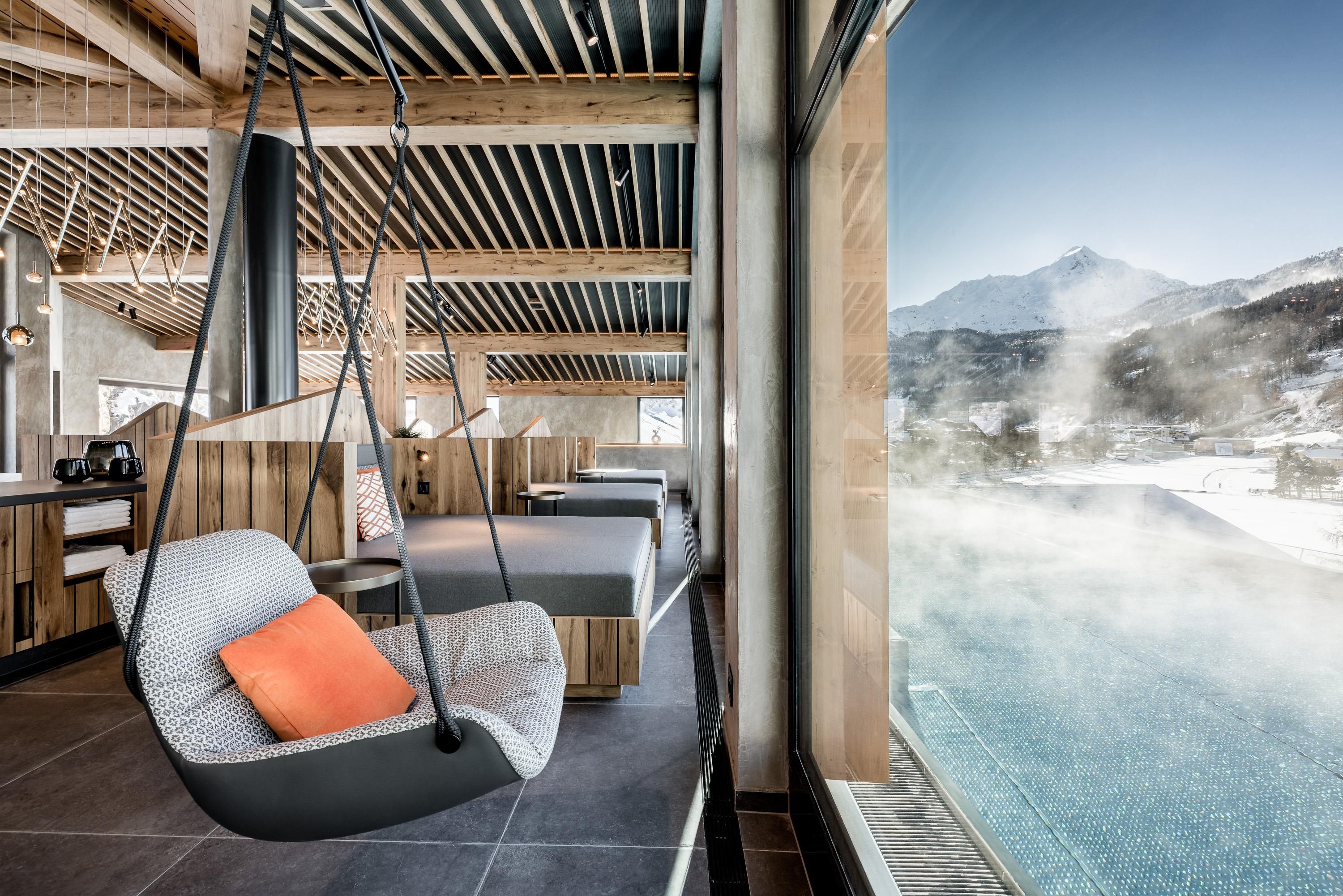 Modern interior design with a floating chair and a large window.
View of a steaming pool and the mountains in the background.