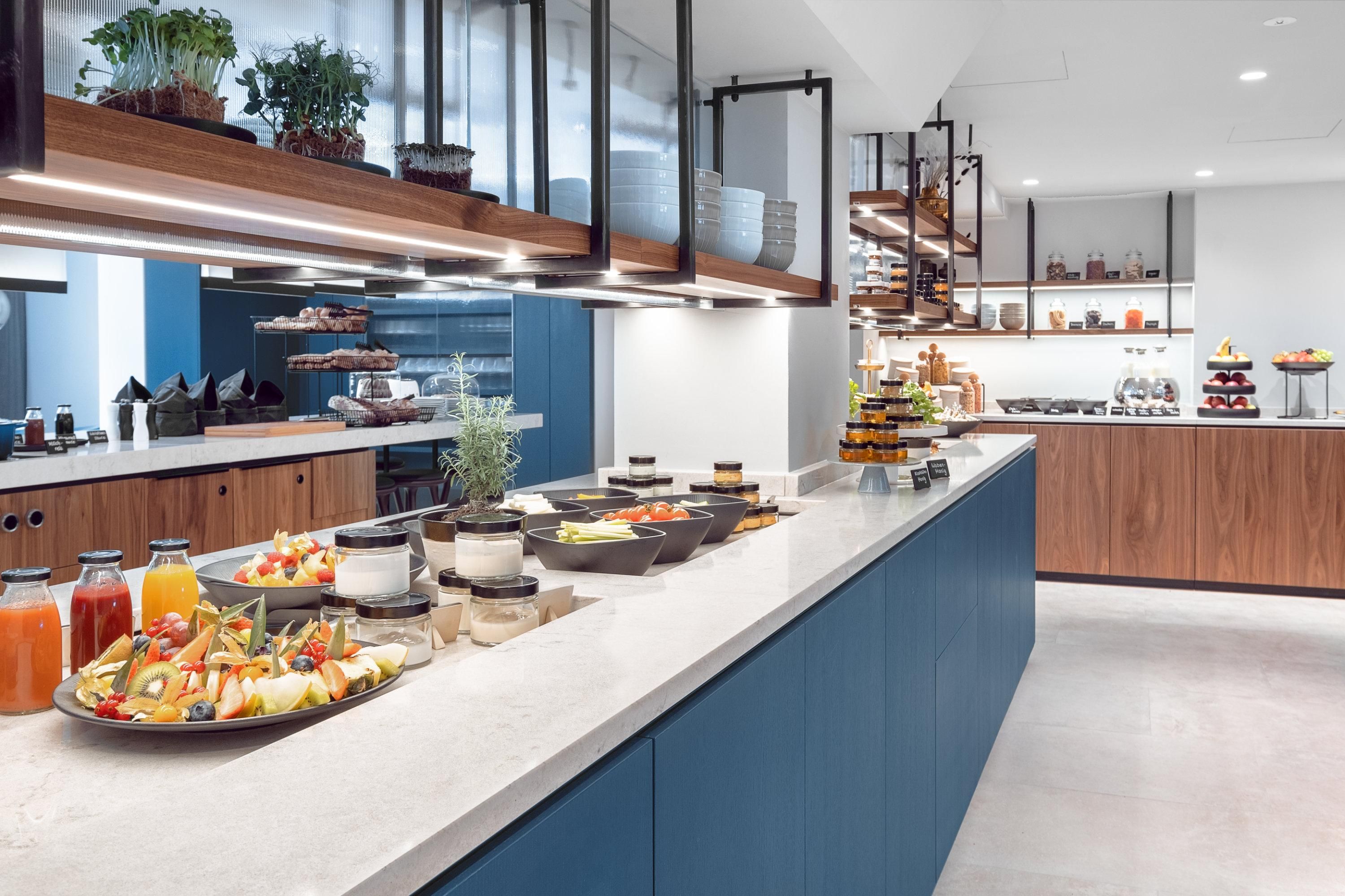 A modern kitchen with a wide selection of food and drinks. Fresh fruits, snacks, and decorative elements are placed on the counter.